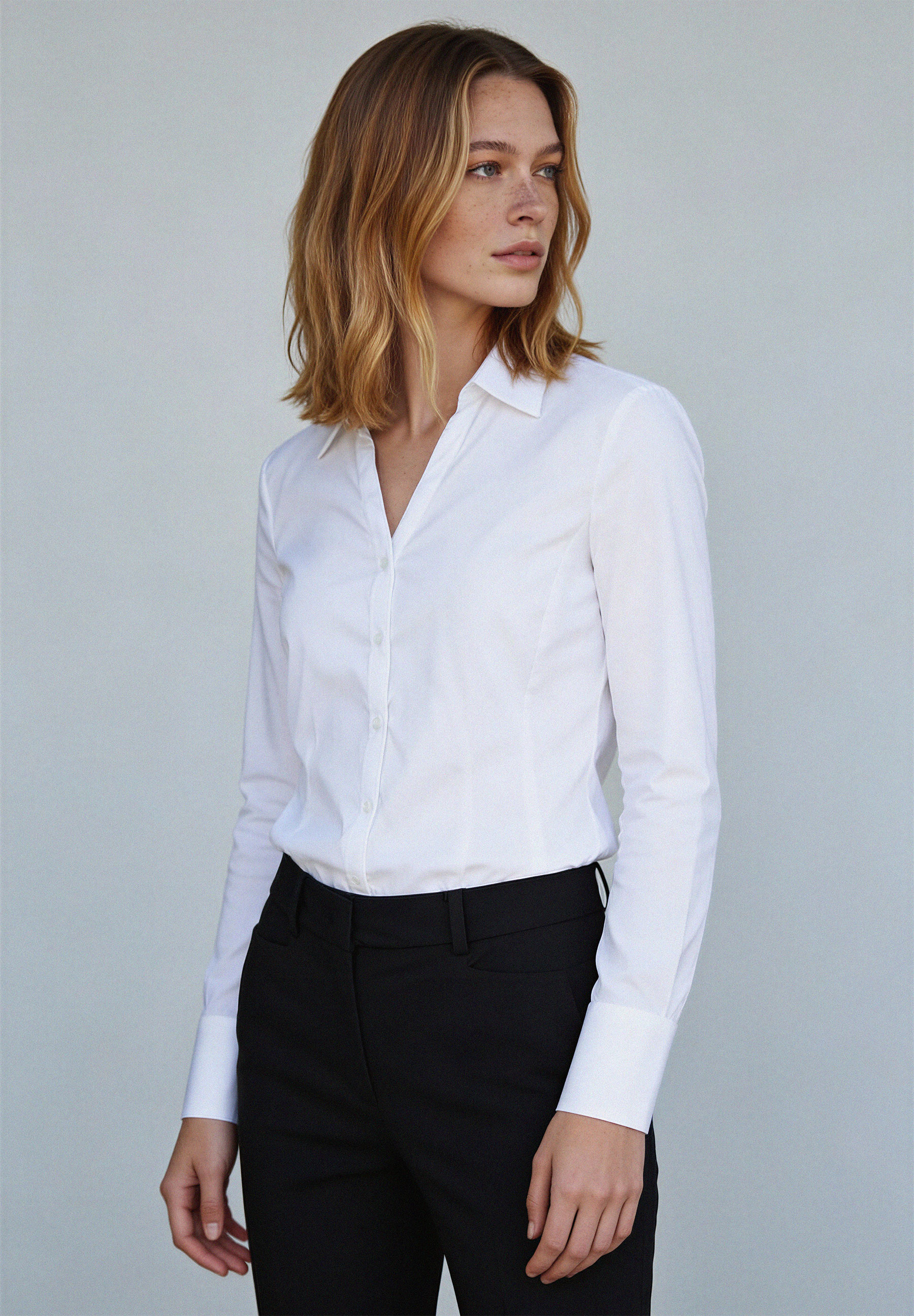 Eine Frau trägt eine weiße Bluse von MORE & MORE. Die Baumwollmischung bietet Stretch für angenehmen Tragekomfort.