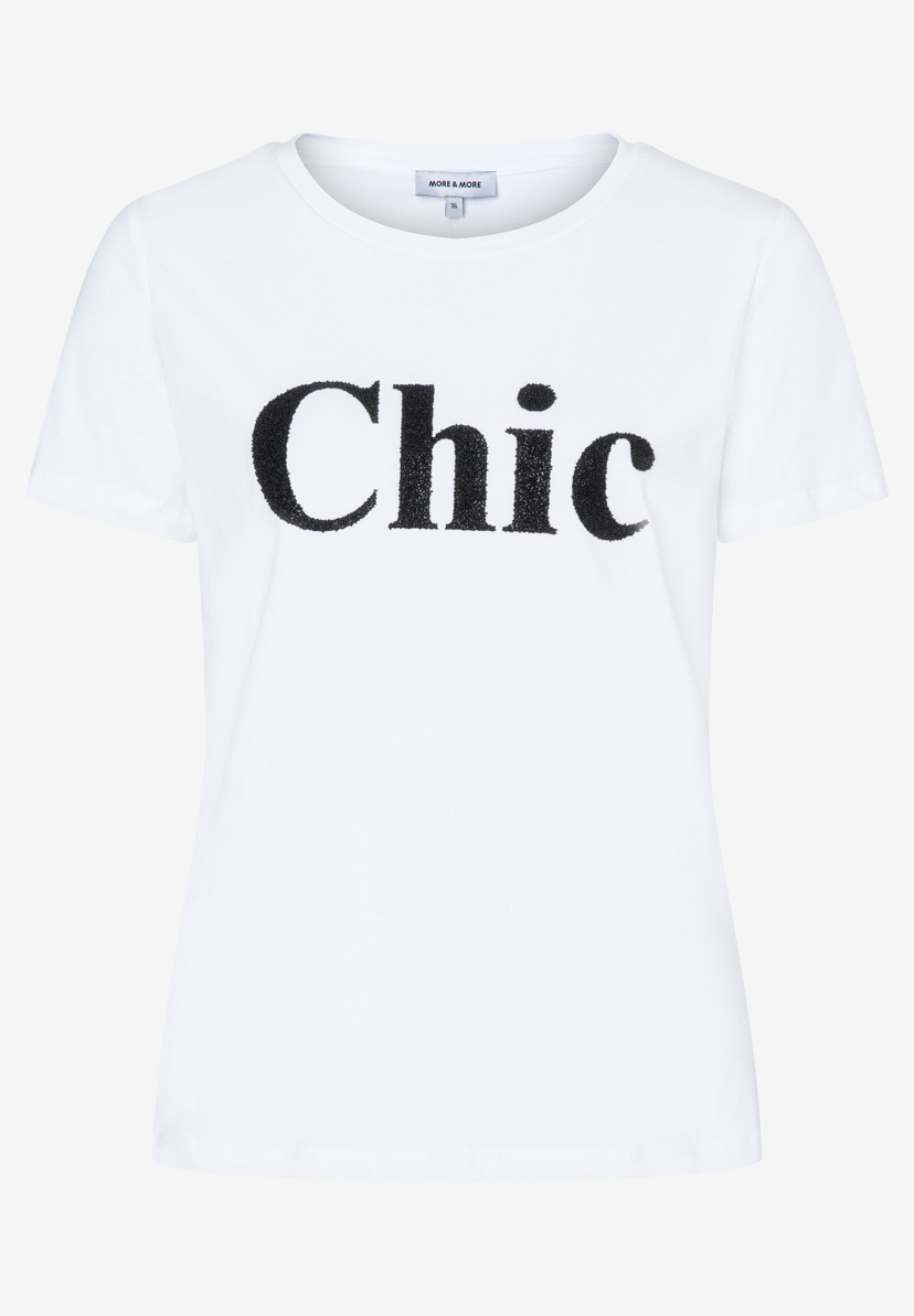 Ein weißes MORE & MORE T-Shirt mit dem glitzernden schwarzen Schriftzug "Chic". Ein weißes MORE & MORE T-Shirt mit dem glitzernden schwarzen Schriftzug "Chic".