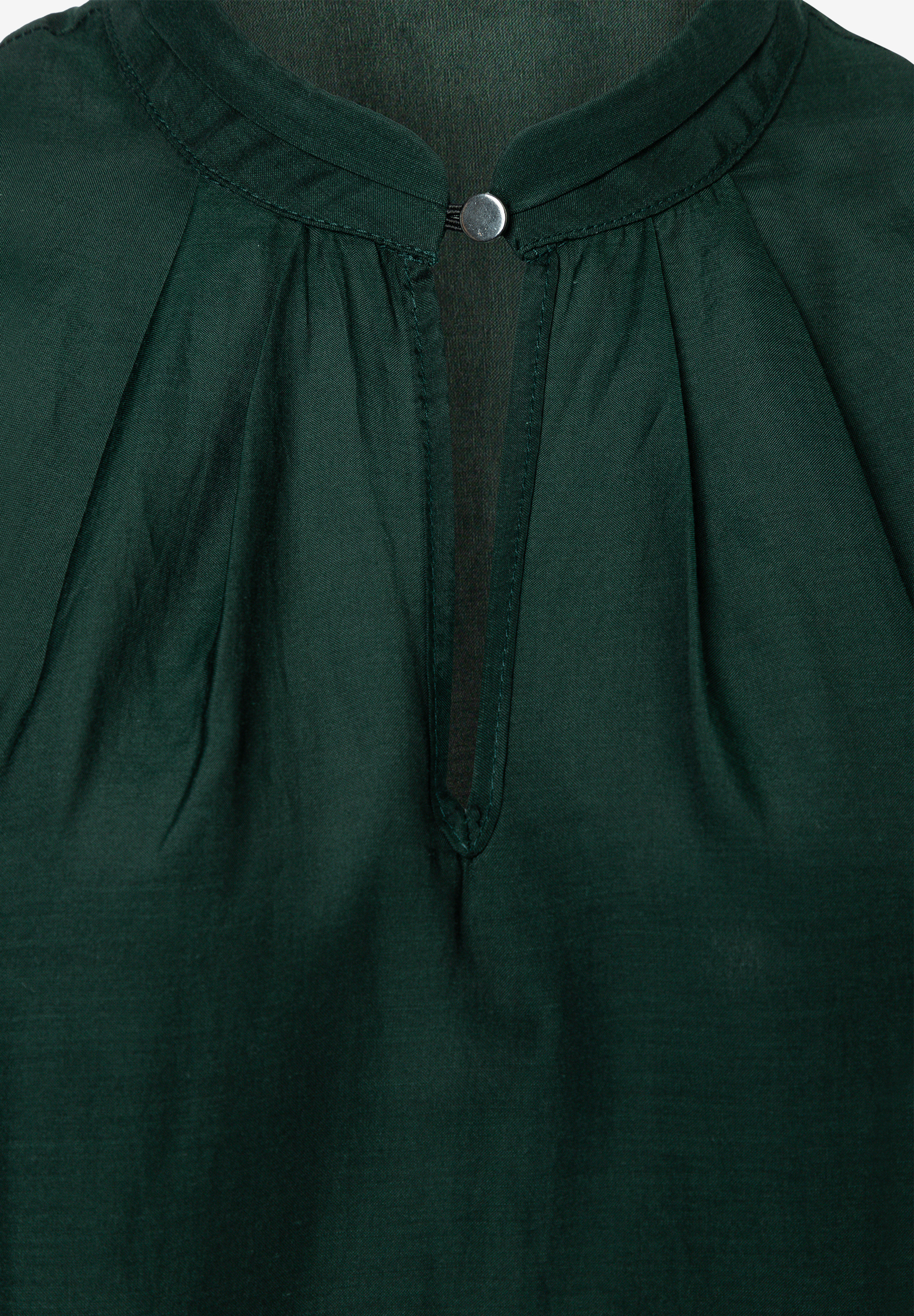 MORE & MORE Bluse in Dunkelgrün mit Stehkragen und gerafftem Ausschnitt, der mit einem silbernen Knopf verschlossen ist. MORE & MORE Bluse in Dunkelgrün mit Stehkragen und gerafftem Ausschnitt, der mit einem silbernen Knopf verschlossen ist.