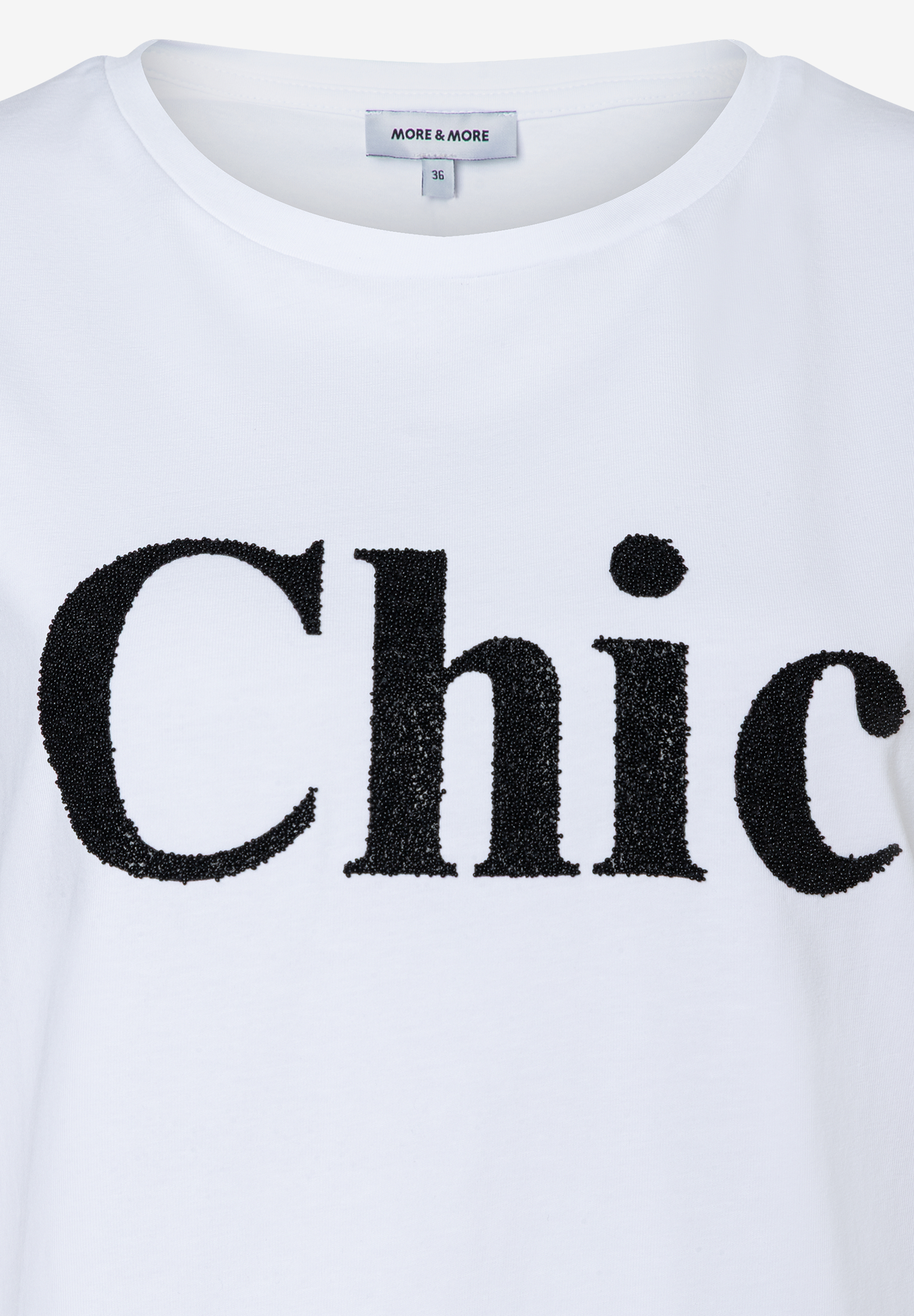 Ein weißes T-Shirt von MORE & MORE mit schwarzem "Chic"-Schriftzug. Ein weißes T-Shirt von MORE & MORE mit schwarzem "Chic"-Schriftzug.