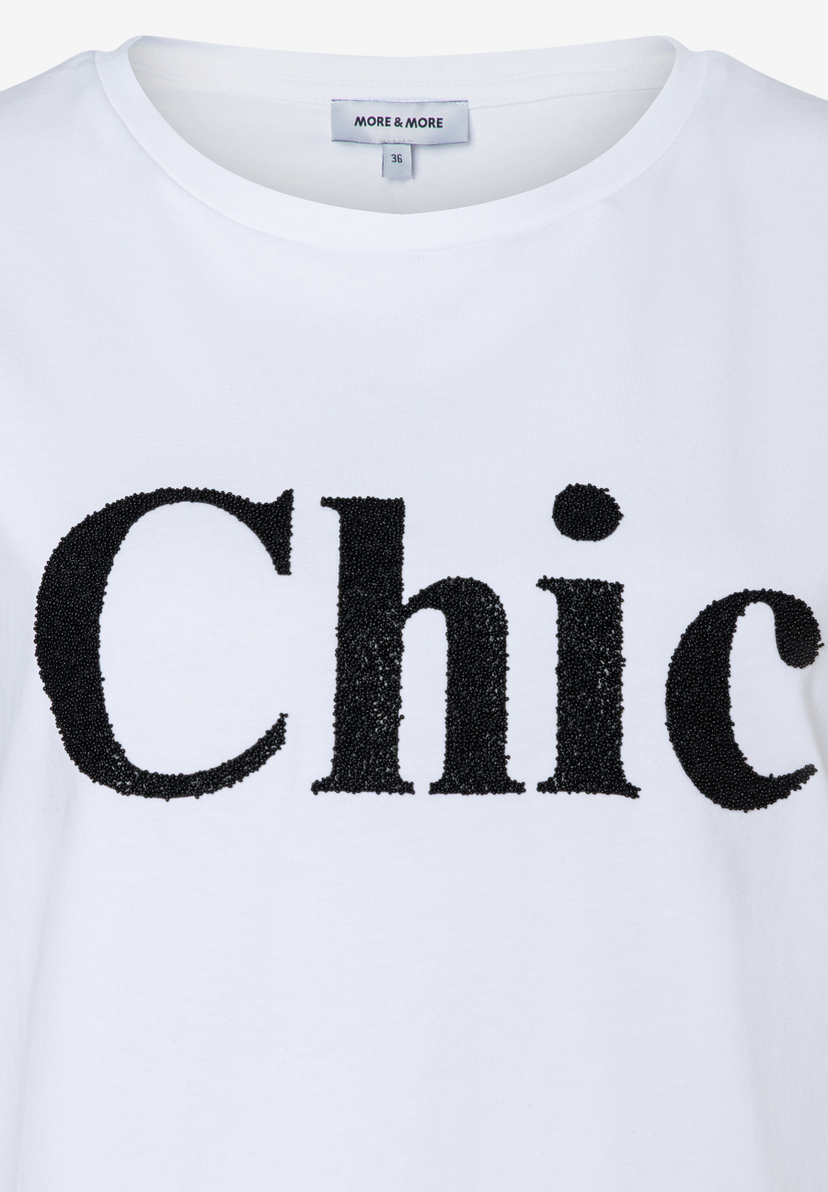 Ein weißes T-Shirt von MORE & MORE mit schwarzem "Chic"-Schriftzug. Ein weißes T-Shirt von MORE & MORE mit schwarzem "Chic"-Schriftzug.