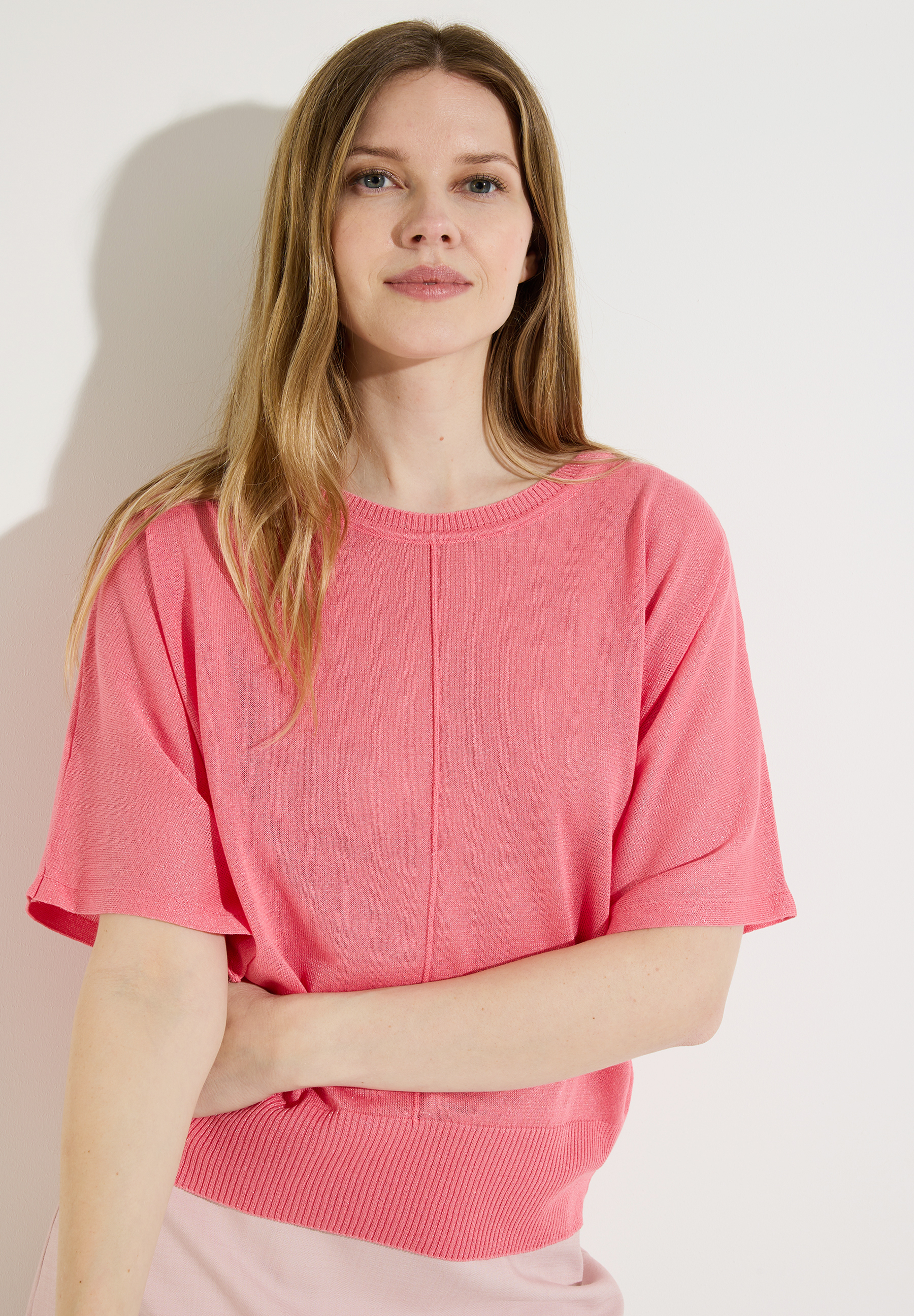 Eine Frau mit MORE & MORE Oberteil/Feinstrick in Koralle vor weißem Hintergrund.