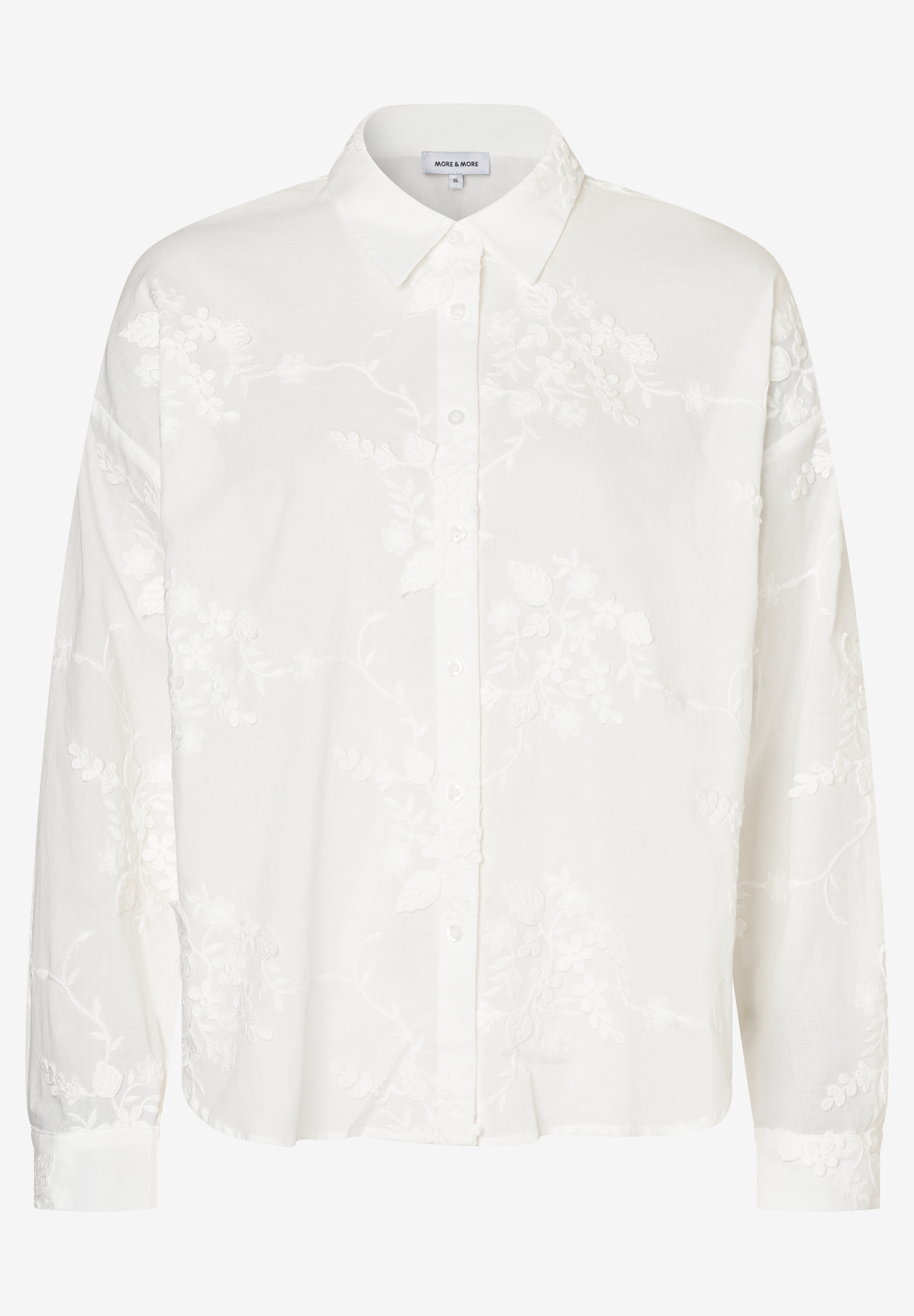 Eine weiße, langärmlige MORE & MORE Bluse mit floralen Stickereien und Knopfleiste.
