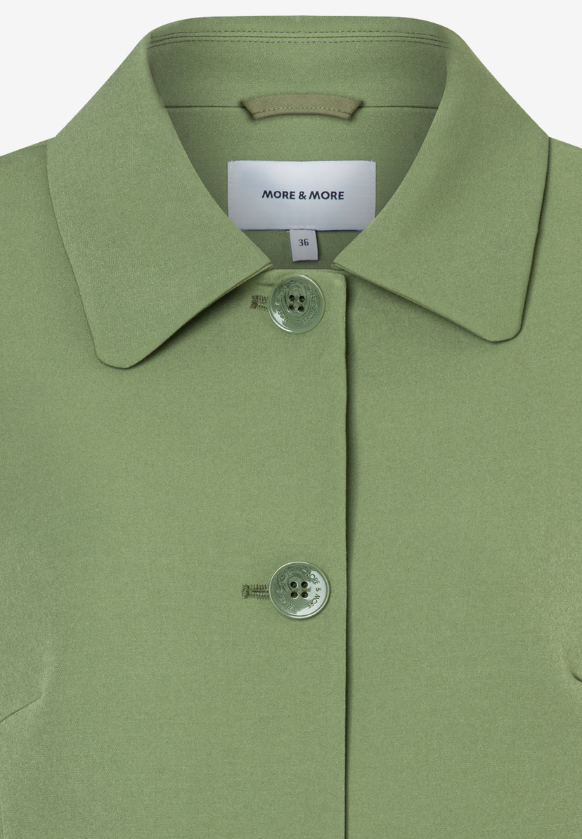 Nahaufnahme eines grünen MORE & MORE Blazers mit Knöpfen und Kragen. Nahaufnahme eines grünen MORE & MORE Blazers mit Knöpfen und Kragen.