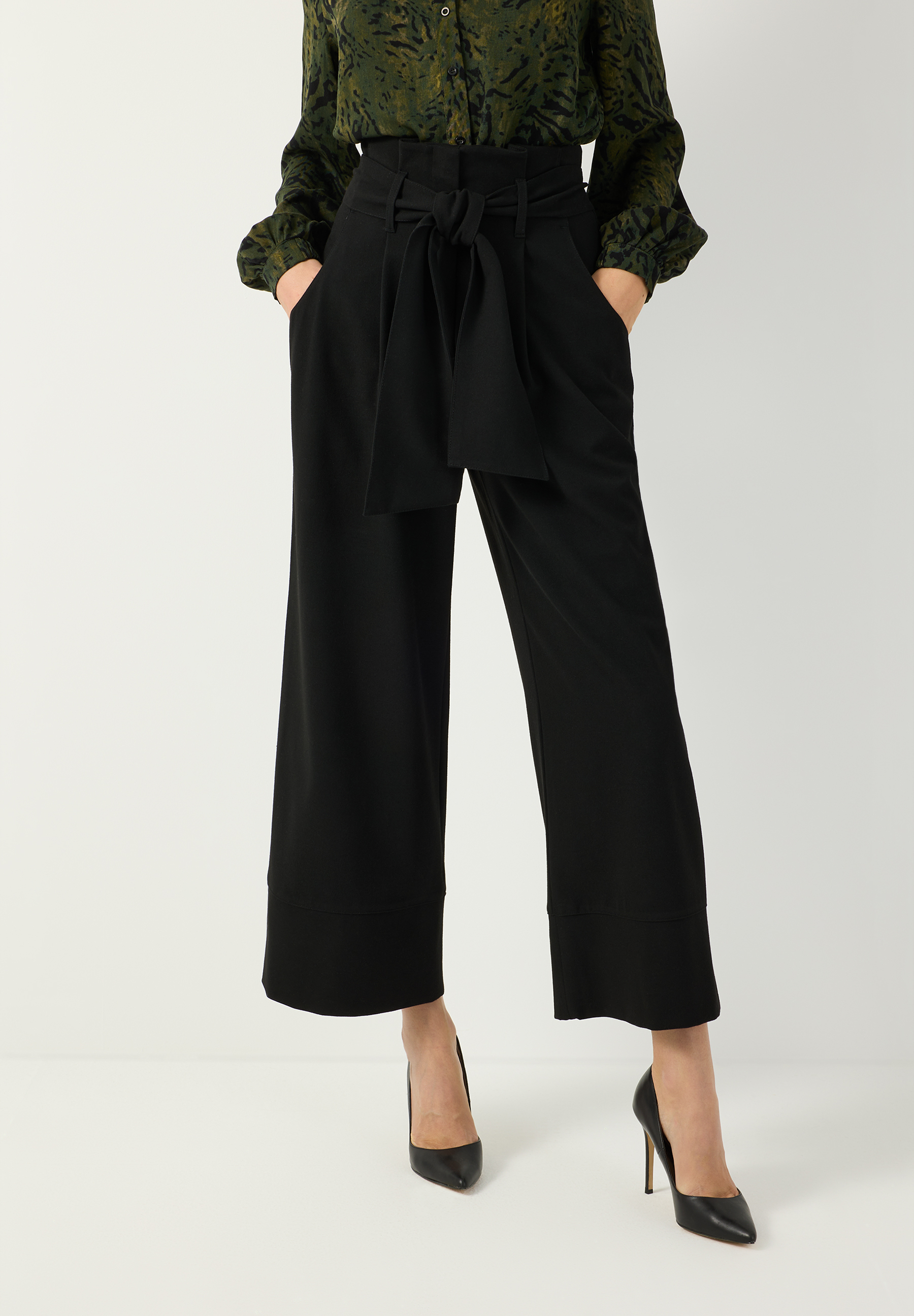 MORE & MORE schwarze Palazzo-Hose mit hohem Bund und Bindegürtel, dazu dunkelgrüne Bluse mit Muster und schwarzen Pumps.