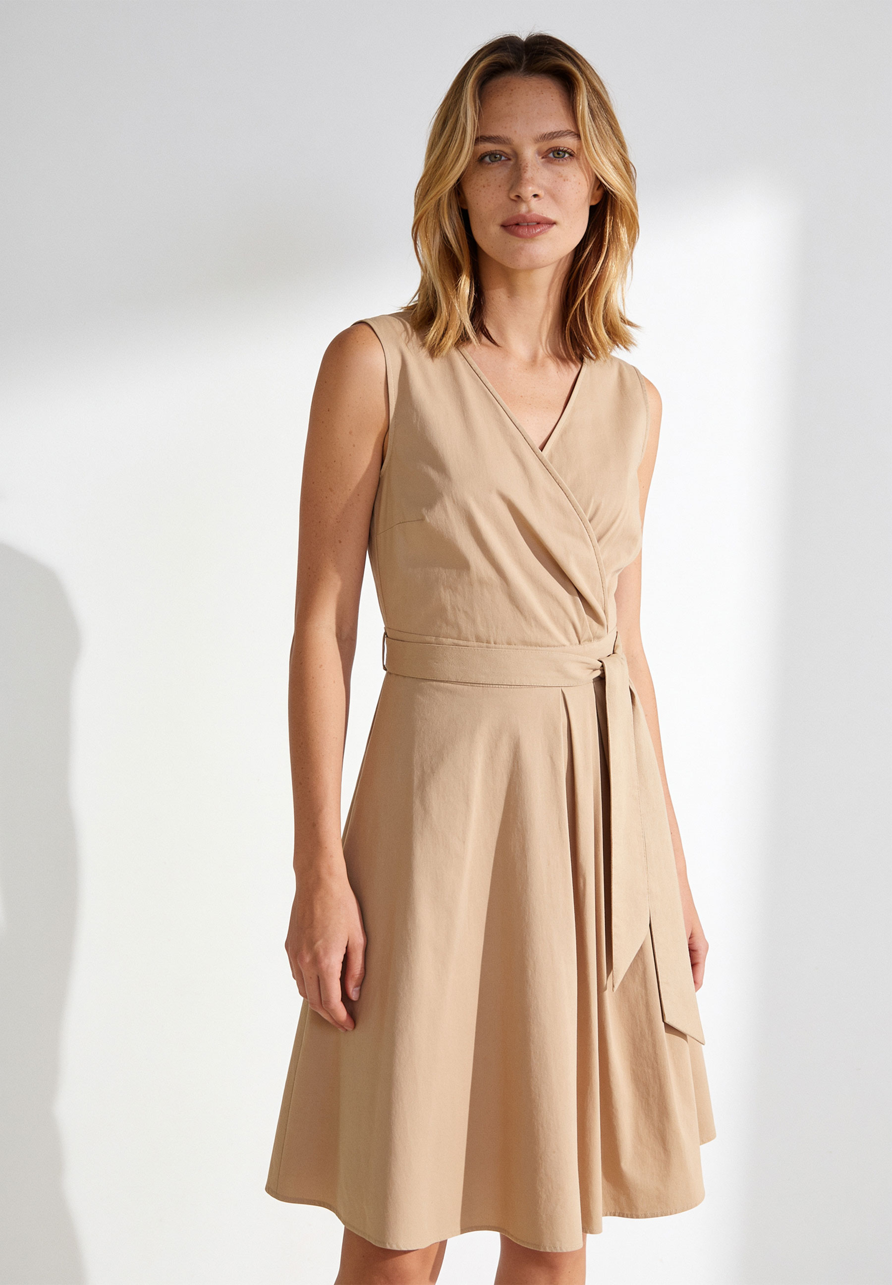 AI generated - MORE & MORE Wickelkleid aus beigem Popeline. Ärmelloses Kleid mit V-Ausschnitt, Wickeloptik und Gürtel.