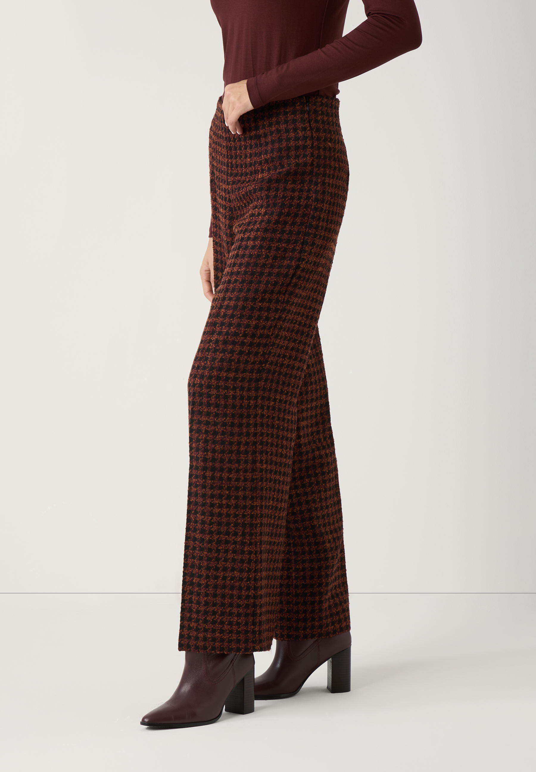 Eine seitliche Nahaufnahme von MORE & MORE Hosen mit Hahnentrittmuster und Stiefeln. Eine seitliche Nahaufnahme von MORE & MORE Hosen mit Hahnentrittmuster und Stiefeln.