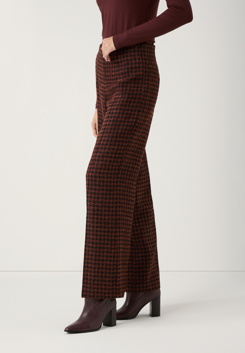 Eine seitliche Nahaufnahme von MORE & MORE Hosen mit Hahnentrittmuster und Stiefeln. Eine seitliche Nahaufnahme von MORE & MORE Hosen mit Hahnentrittmuster und Stiefeln.