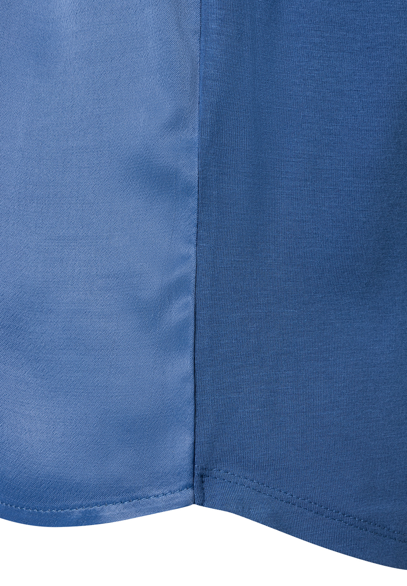 Detailaufnahme eines blau geteilten Oberteils von MORE & MORE, das verschiedene Texturen zeigt. Detailaufnahme eines blau geteilten Oberteils von MORE & MORE, das verschiedene Texturen zeigt.