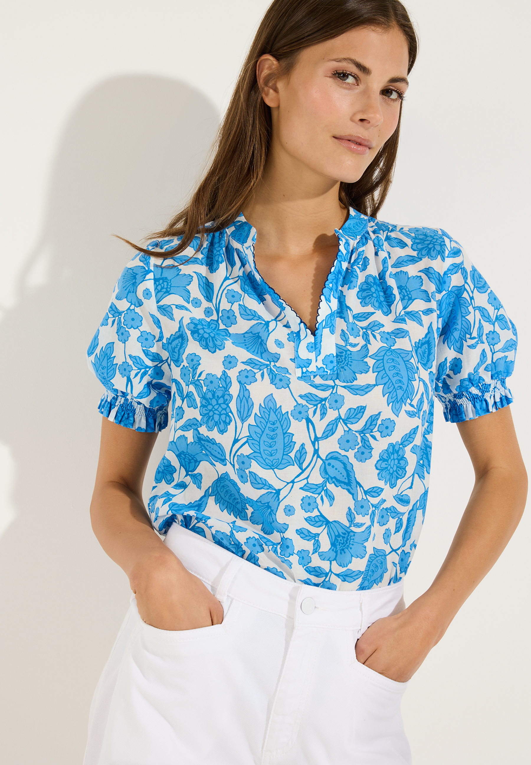 MORE & MORE Bluse mit blauen Blumenmuster kombiniert zu weißer Hose. Ideal für Sommeroutfits.