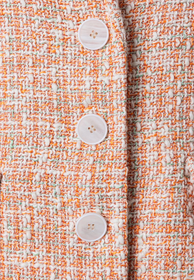 Nahaufnahme eines formstabilen MORE & MORE Blazers aus Bouclé mit drei weißen Knöpfen. Nahaufnahme eines formstabilen MORE & MORE Blazers aus Bouclé mit drei weißen Knöpfen.