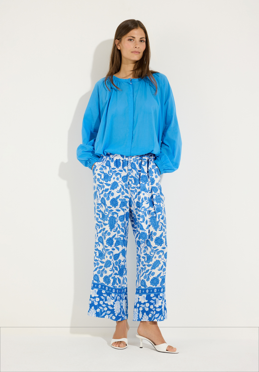 MORE & MORE Bluse und Hose: Frau in türkiser leichter Baumwollbluse und blau-weiß gemusterter Hose. MORE & MORE Bluse und Hose: Frau in türkiser leichter Baumwollbluse und blau-weiß gemusterter Hose.