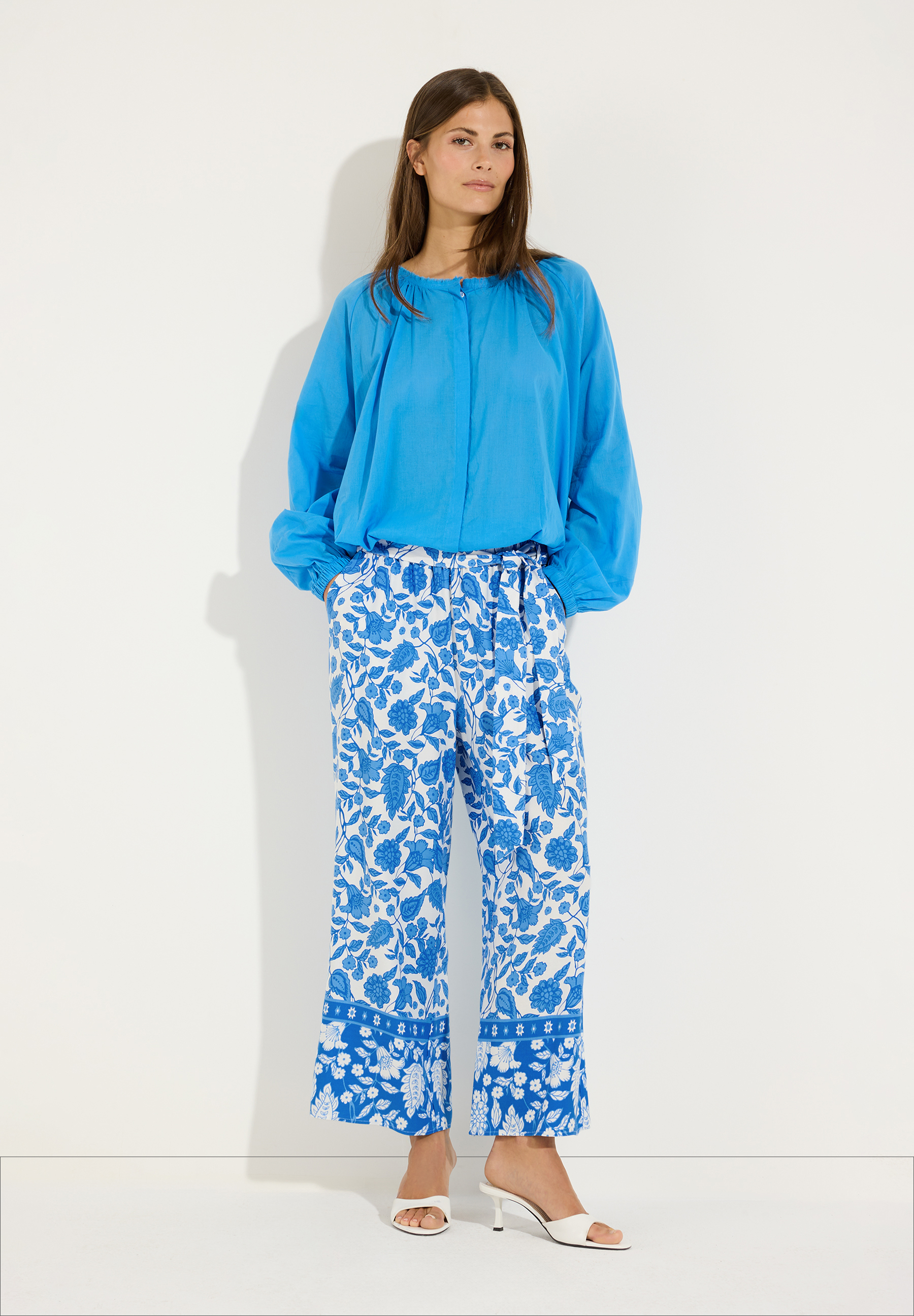 MORE & MORE Bluse und Hose: Frau in türkiser leichter Baumwollbluse und blau-weiß gemusterter Hose. MORE & MORE Bluse und Hose: Frau in türkiser leichter Baumwollbluse und blau-weiß gemusterter Hose.