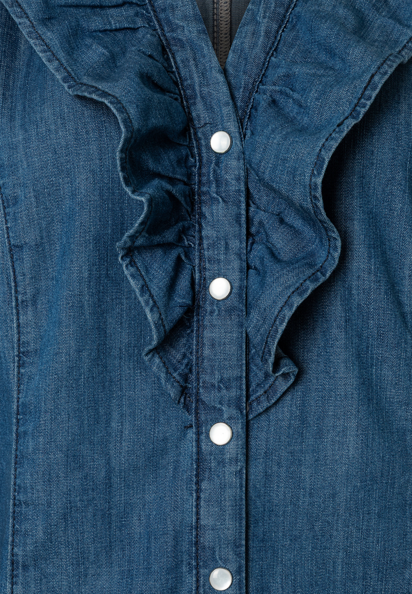 Nahaufnahme einer blauen MORE & MORE Bluse mit Rüschen und vier weißen Knöpfen. Nahaufnahme einer blauen MORE & MORE Bluse mit Rüschen und vier weißen Knöpfen.