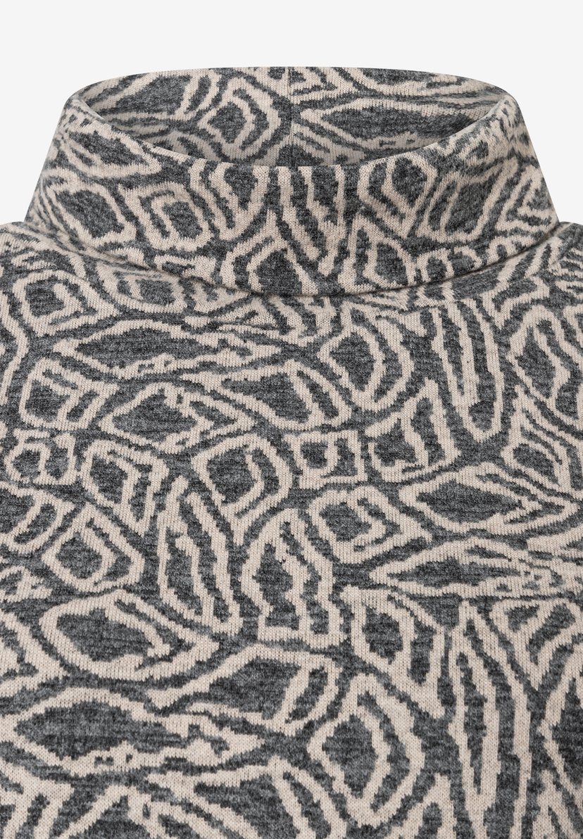 Nahaufnahme eines MORE & MORE Oberteils mit abstraktem Muster und Rollkragen. Nahaufnahme eines MORE & MORE Oberteils mit abstraktem Muster und Rollkragen.