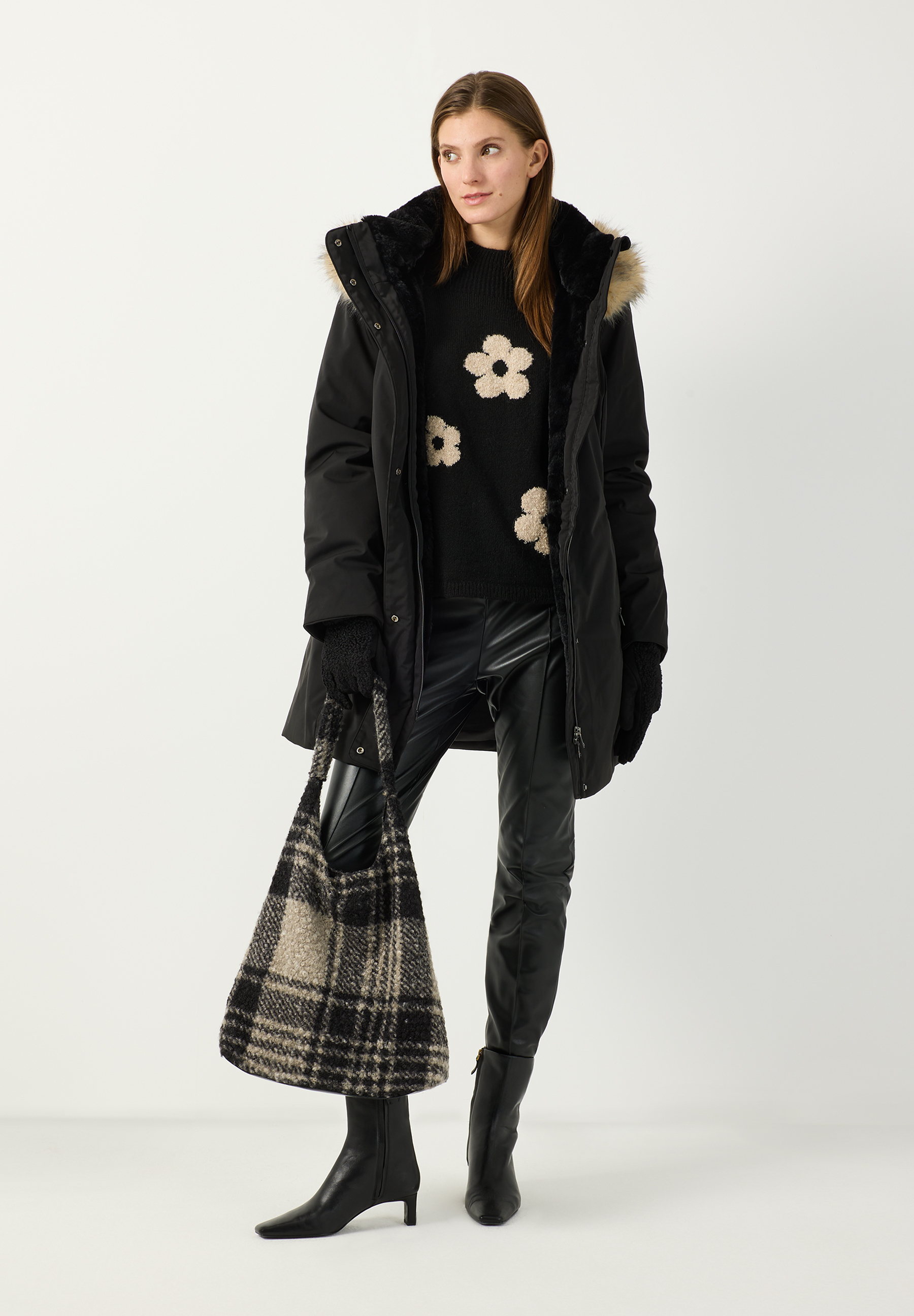 MORE & MORE schwarze Webware-Jacke mit kuscheligem Kunstfellkragen. Die wärmende Jacke hat lange Ärmel und wird mit einem Reißverschluss geschlossen. Dazu trägt das Model eine Jeans und schwarze Stiefel.