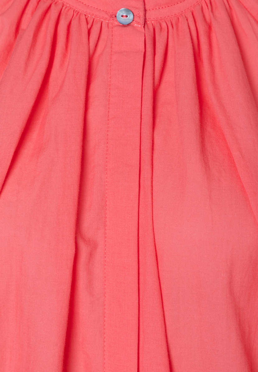 Nahaufnahme einer korallfarbenen MORE & MORE Bluse mit Knopfleiste und blassblauem Knopf am Kragen.