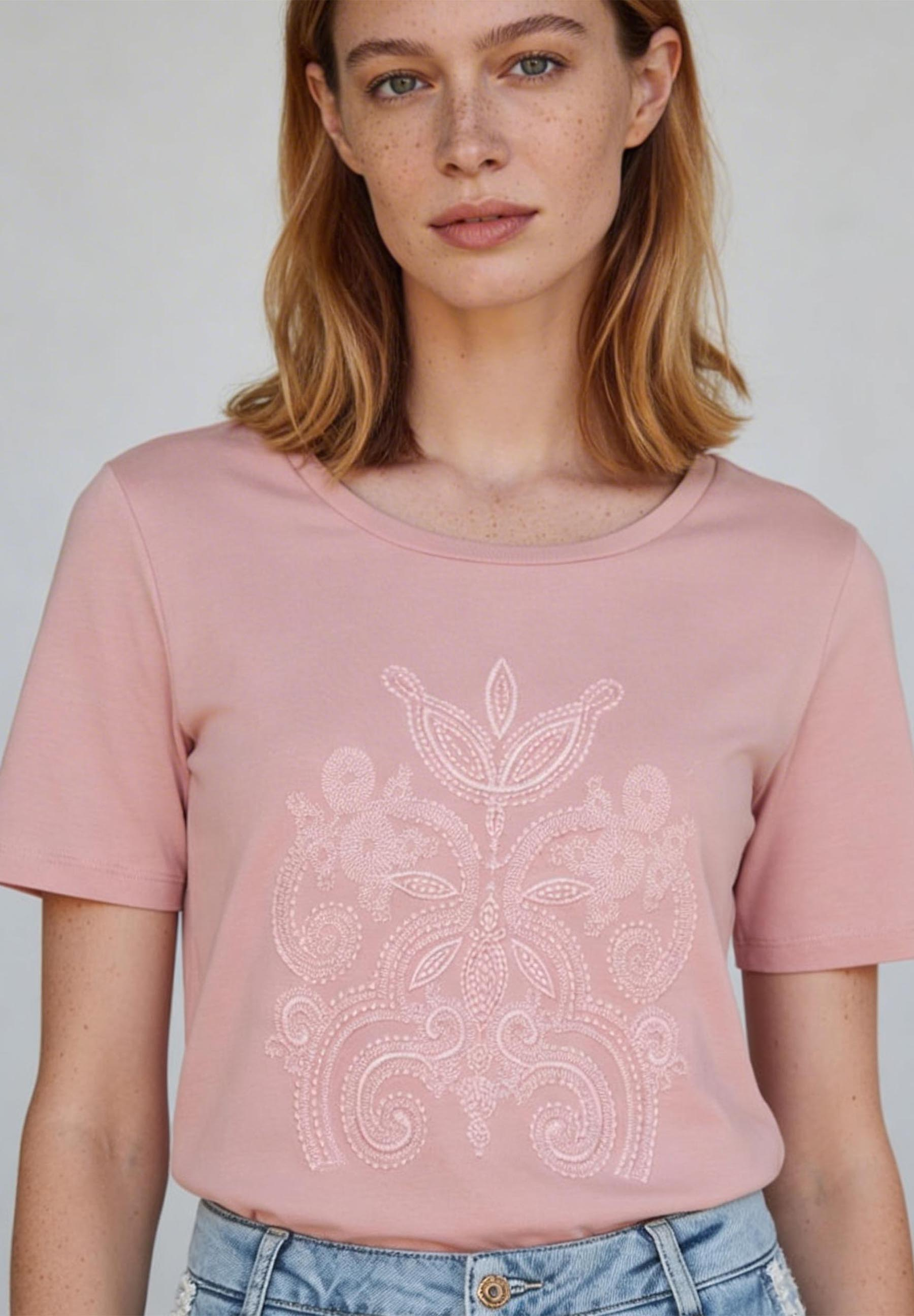 Nahaufnahme eines MORE & MORE Oberteils, Jersey, mit hellrosa Stickerei auf rosafarbenem Grund.