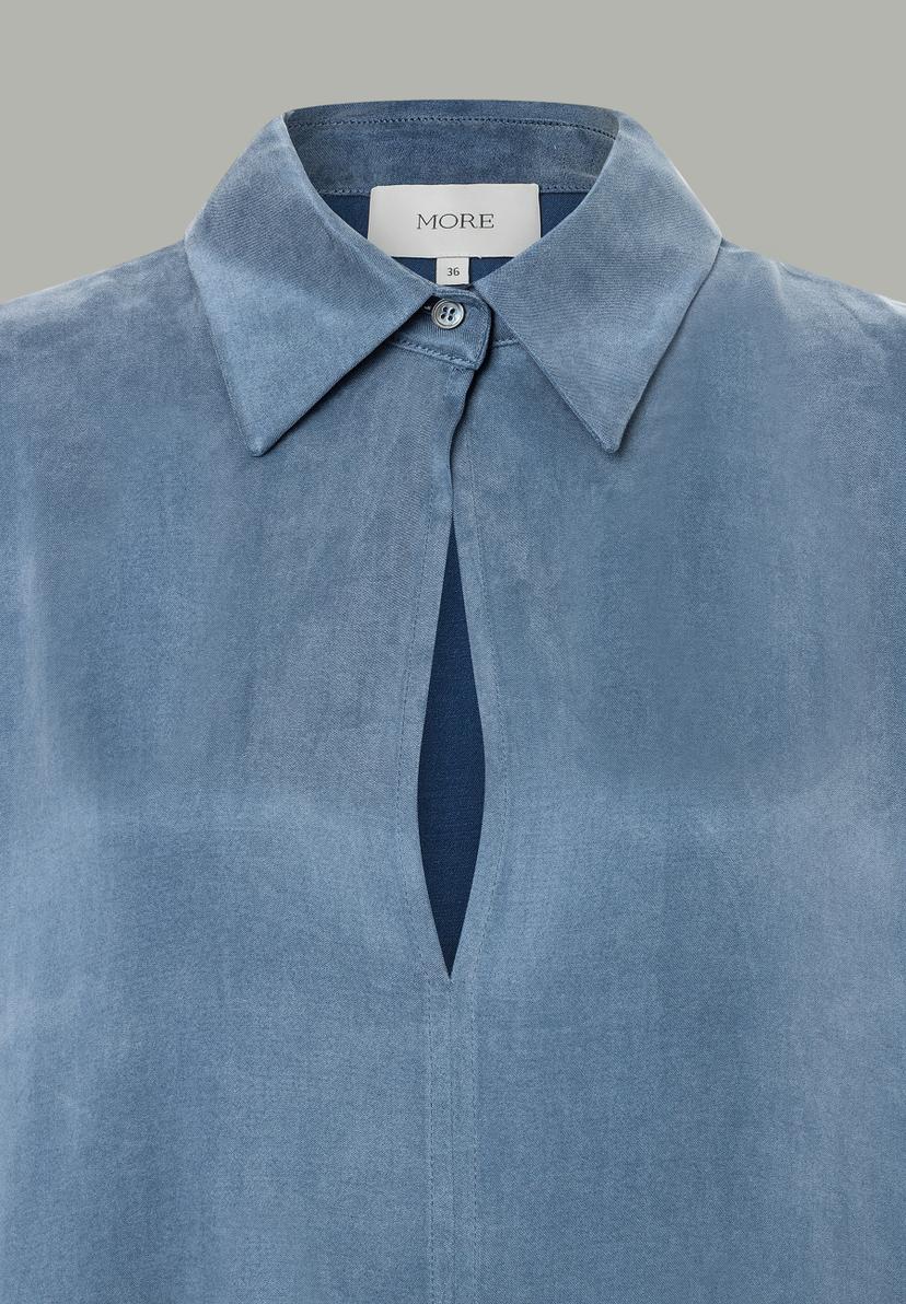 Nahaufnahme einer blauen MORE & MORE Bluse mit Kragen und Knopfdetail. Nahaufnahme einer blauen MORE & MORE Bluse mit Kragen und Knopfdetail.