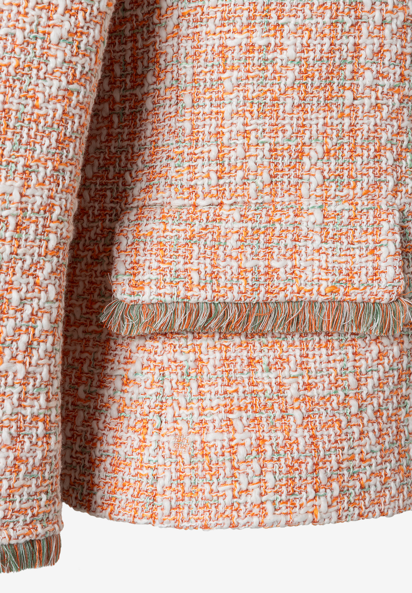 Nahaufnahme eines MORE & MORE Blazers mit Bouclé-Textur und Fransen-Detail. Nahaufnahme eines MORE & MORE Blazers mit Bouclé-Textur und Fransen-Detail.