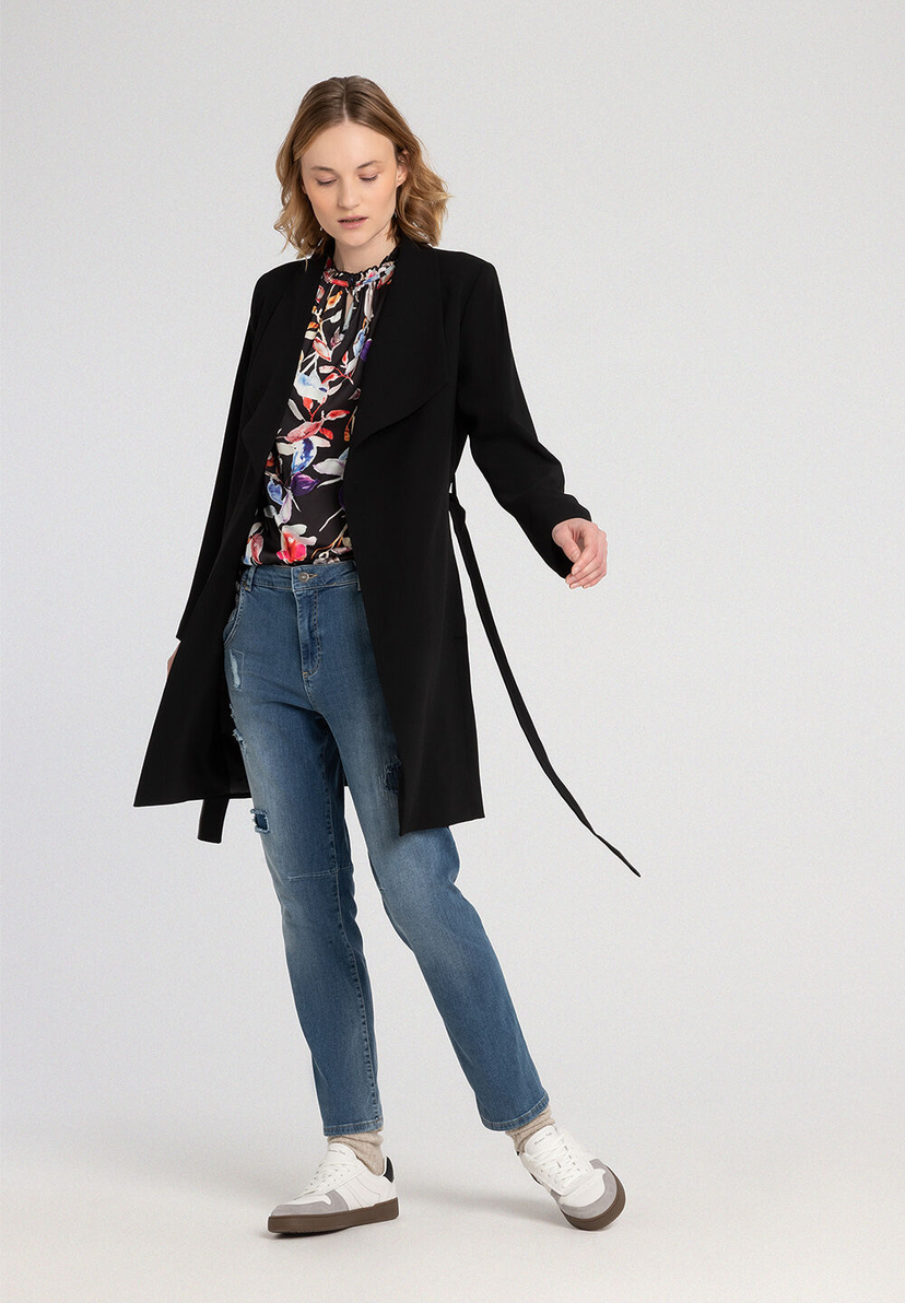 Eine Frau in MORE & MORE Jeans und schwarzem Mantel posiert vor einem neutralen Hintergrund. Eine Frau in MORE & MORE Jeans und schwarzem Mantel posiert vor einem neutralen Hintergrund.