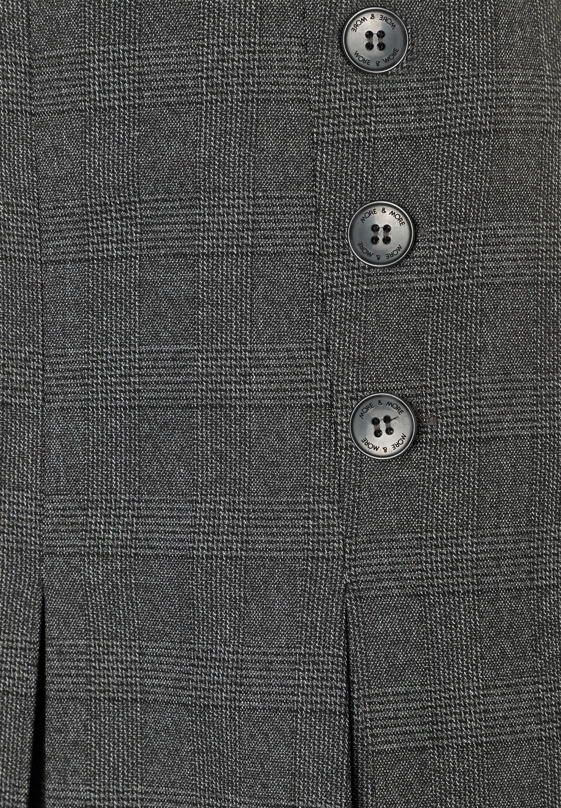 Nahaufnahme eines MORE & MORE Rocks mit Webware-Struktur und Knöpfen, die den Markennamen zeigen. Nahaufnahme eines MORE & MORE Rocks mit Webware-Struktur und Knöpfen, die den Markennamen zeigen.