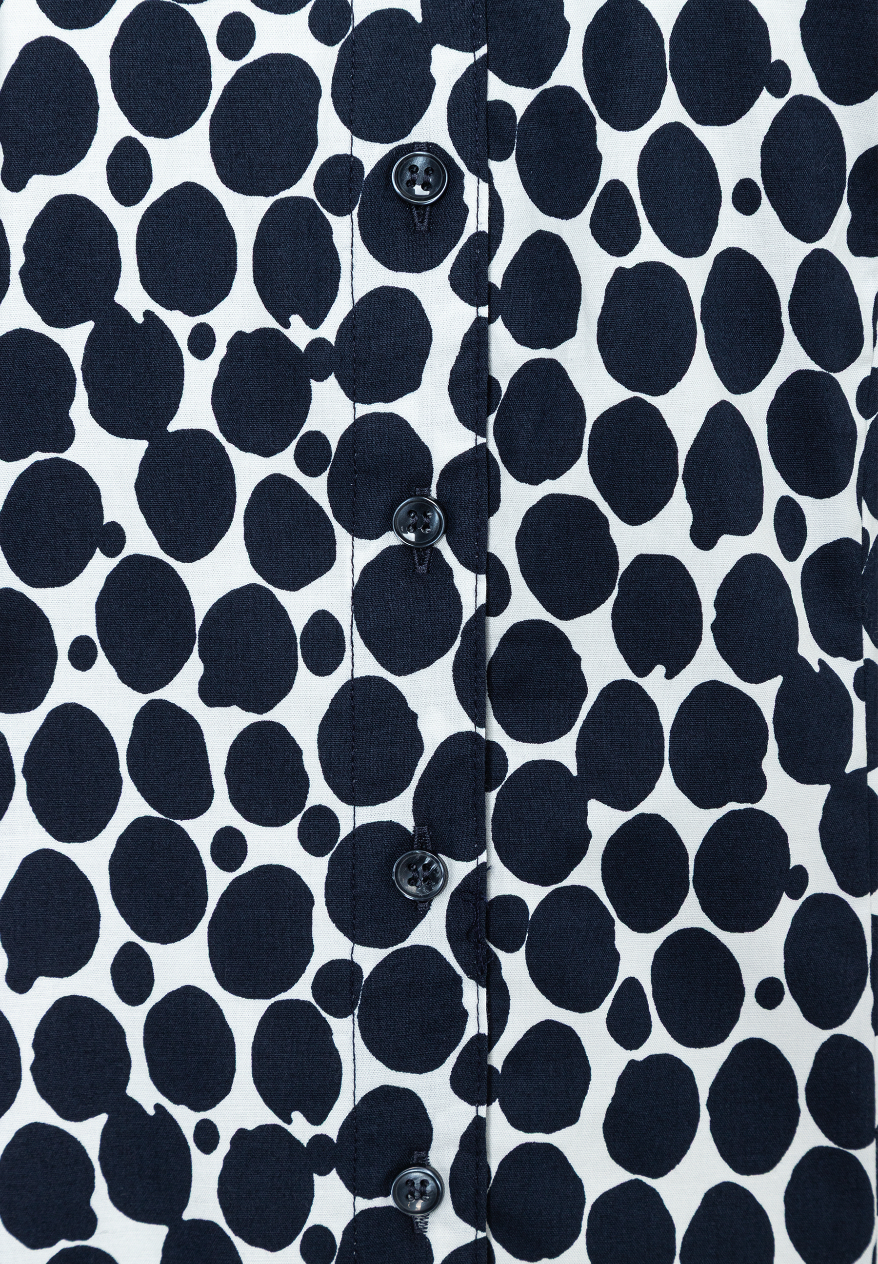 Nahaufnahme einer MORE & MORE Bluse mit schwarzen Punkten und Knopfleiste. Nahaufnahme einer MORE & MORE Bluse mit schwarzen Punkten und Knopfleiste.