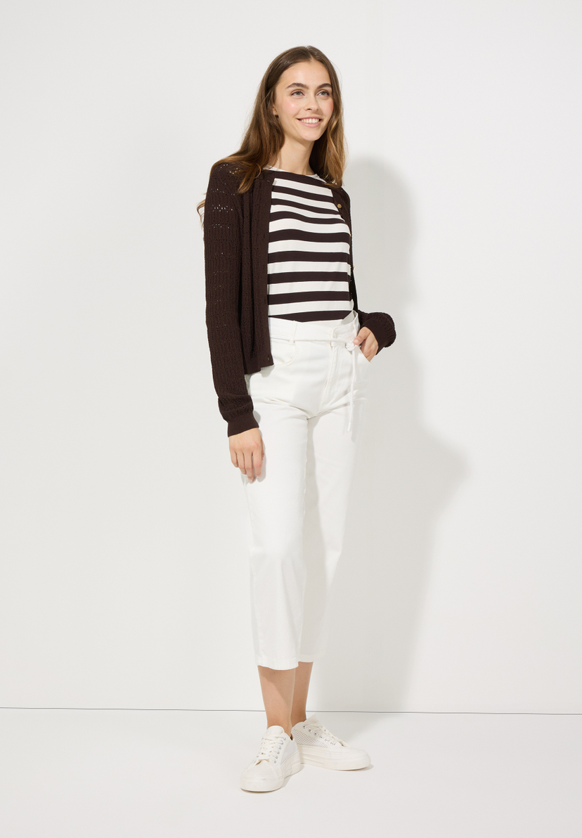 Eine schlanke Frau trägt ein MORE & MORE Jersey-Top mit Streifen, eine Strickjacke und weiße Hosen. Eine schlanke Frau trägt ein MORE & MORE Jersey-Top mit Streifen, eine Strickjacke und weiße Hosen.