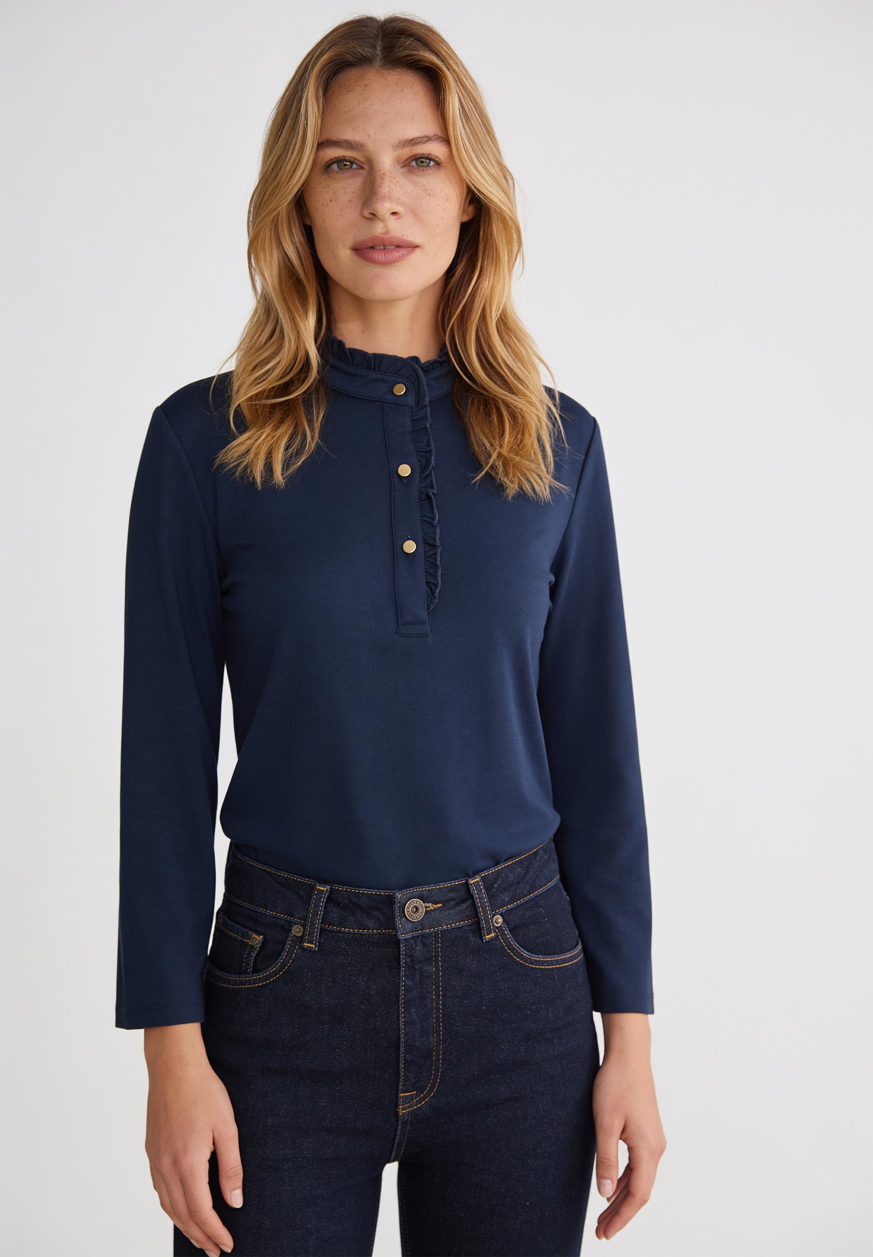 AI generated - MORE & MORE Jersey-Oberteil in Dunkelblau mit Rüschen am Kragen und goldfarbenen Knöpfen, kombiniert mit dunkler Jeans.