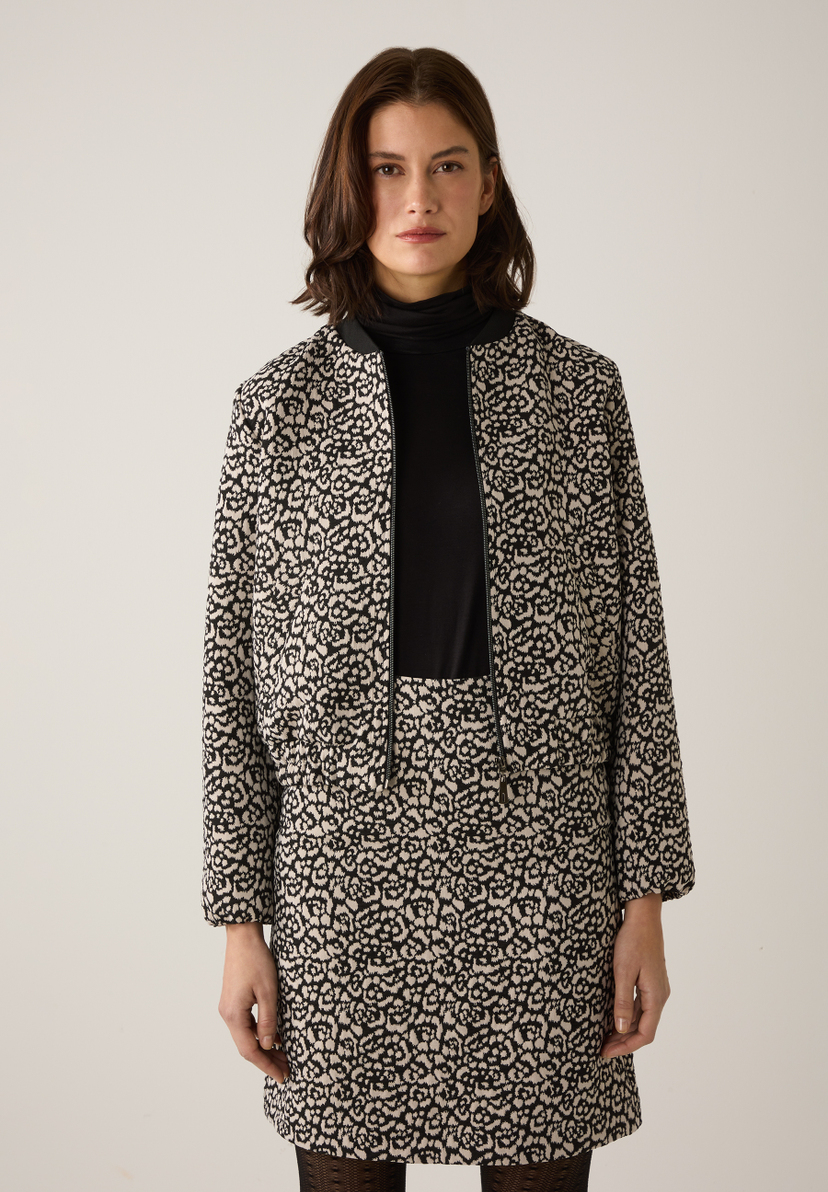 Eine Frau mit MORE & MORE Blazer und passendem Rock mit floralem Muster. Eine Frau mit MORE & MORE Blazer und passendem Rock mit floralem Muster.