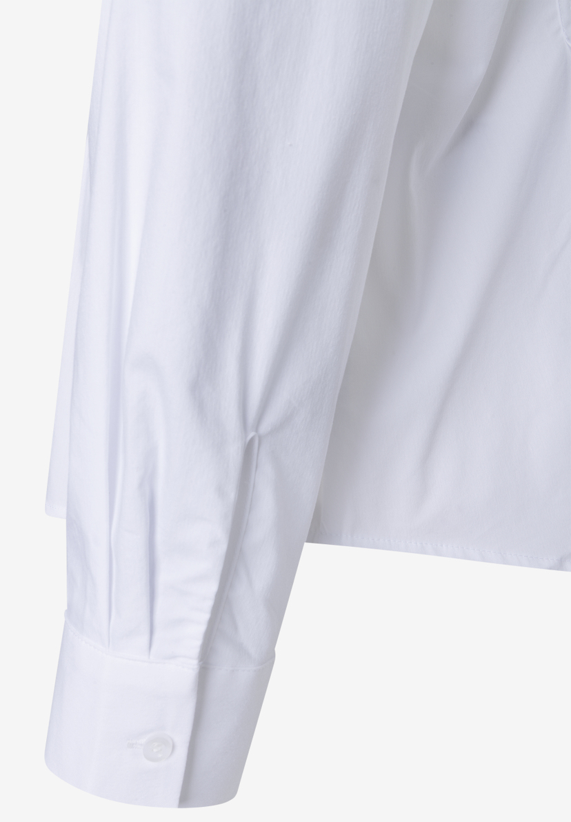 MORE & MORE Bluse: Detailaufnahme eines Ärmels aus weißem Stoff mit Manschette und Knopf.