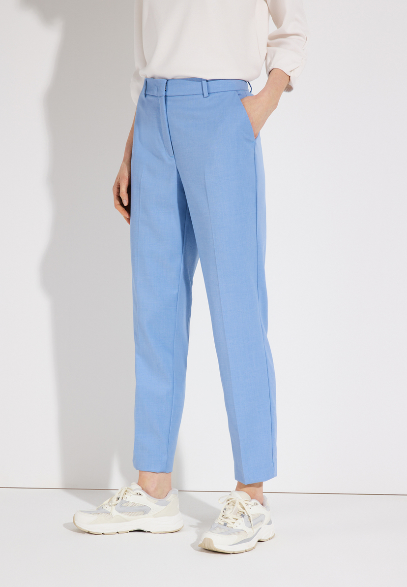 Eine Frau trägt hellblaue MORE & MORE Stretch-Hosen und braune Schuhe vor einem weißen Hintergrund. Eine Frau trägt hellblaue MORE & MORE Stretch-Hosen und braune Schuhe vor einem weißen Hintergrund.