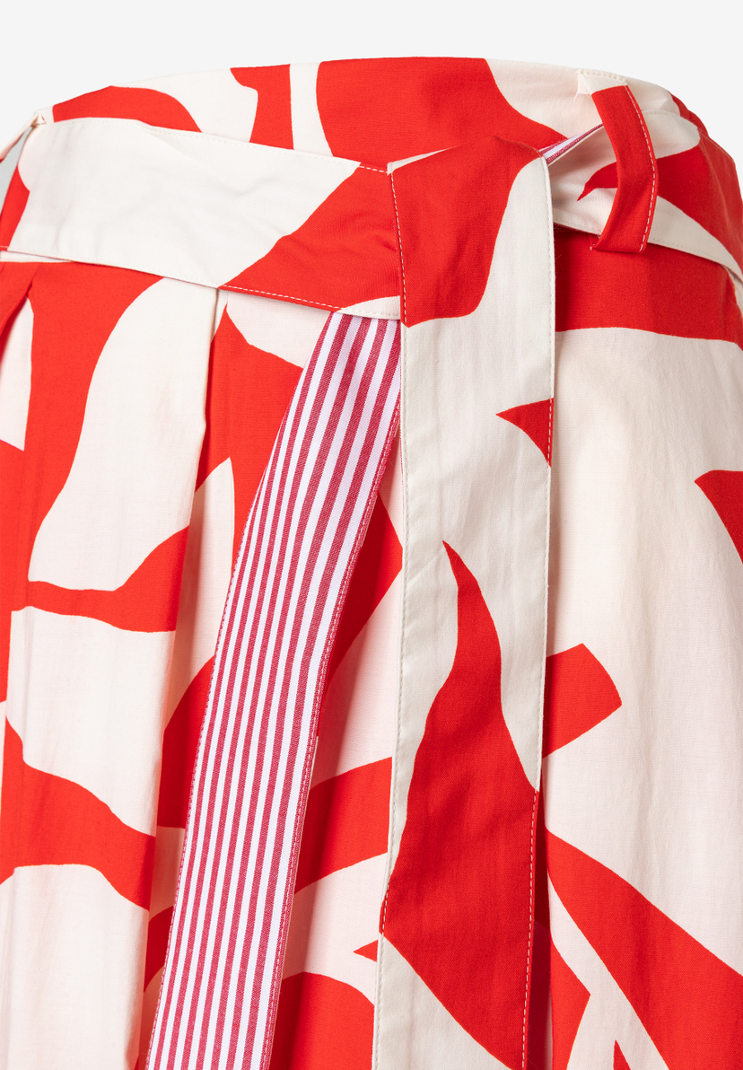 Nahaufnahme eines MORE & MORE Rocks mit rotem Muster und rot-weiß gestreiftem Gürtel. Nahaufnahme eines MORE & MORE Rocks mit rotem Muster und rot-weiß gestreiftem Gürtel.