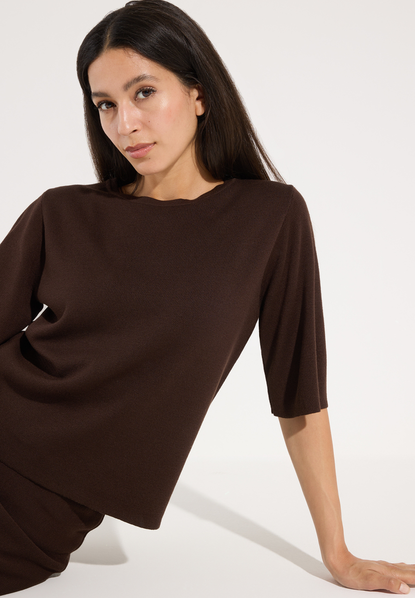 MORE & MORE Damen-Pullover: Eine Frau in einem dunkelbraunen Strickpullover mit halblangen Ärmeln sitzt seitlich. Ihr dunkles Haar fällt offen. MORE & MORE Damen-Pullover: Eine Frau in einem dunkelbraunen Strickpullover mit halblangen Ärmeln sitzt seitlich. Ihr dunkles Haar fällt offen.