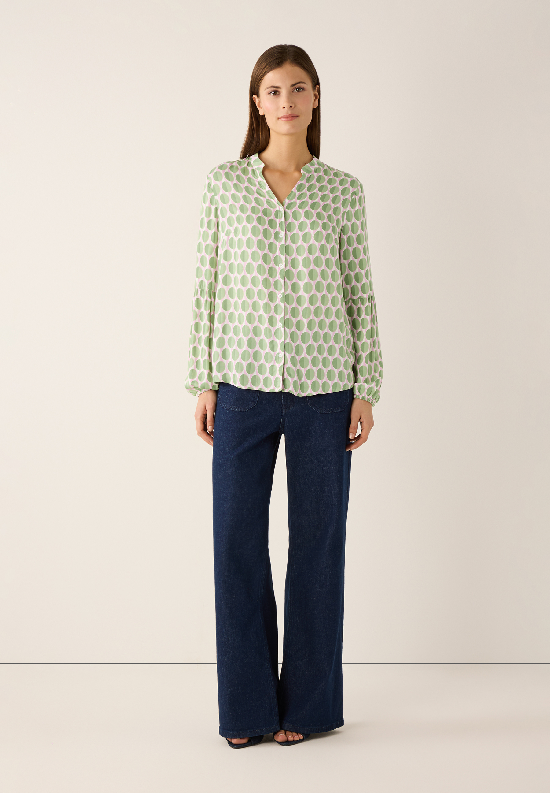 Eine Frau mit einer bedruckten MORE & MORE Bluse, kombiniert mit Jeans, für einen eleganten Look. Eine Frau mit einer bedruckten MORE & MORE Bluse, kombiniert mit Jeans, für einen eleganten Look.