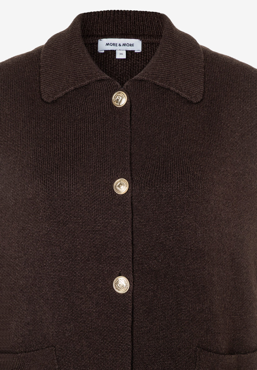 Nahaufnahme eines braunen MORE & MORE Strickoberteils mit Knöpfen und Kragen. Nahaufnahme eines braunen MORE & MORE Strickoberteils mit Knöpfen und Kragen.