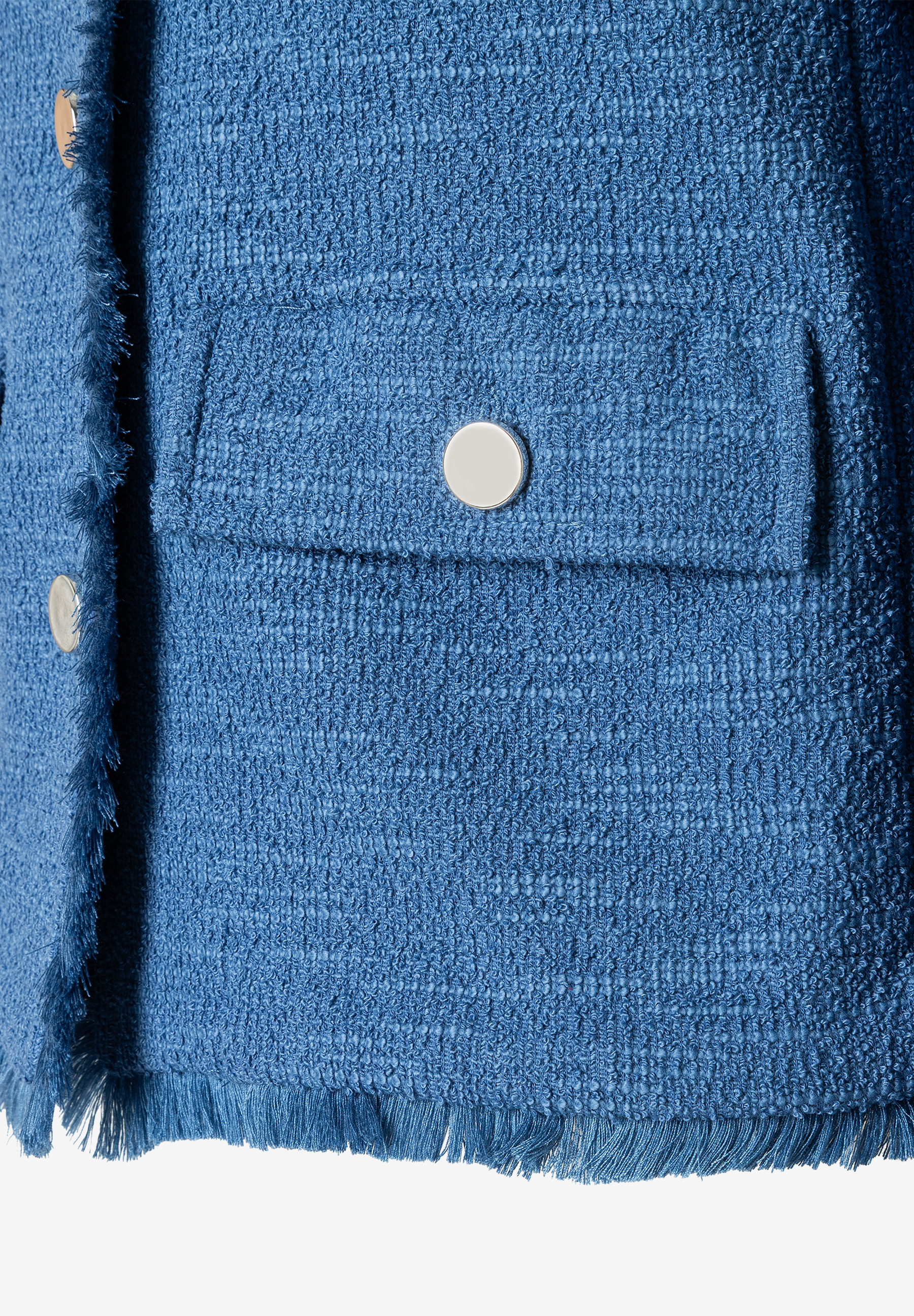 Nahaufnahme eines blauen MORE & MORE Blazers mit Strukturjersey und Bouclé. Silberne Knöpfe und Fransen am Saum. Nahaufnahme eines blauen MORE & MORE Blazers mit Strukturjersey und Bouclé. Silberne Knöpfe und Fransen am Saum.