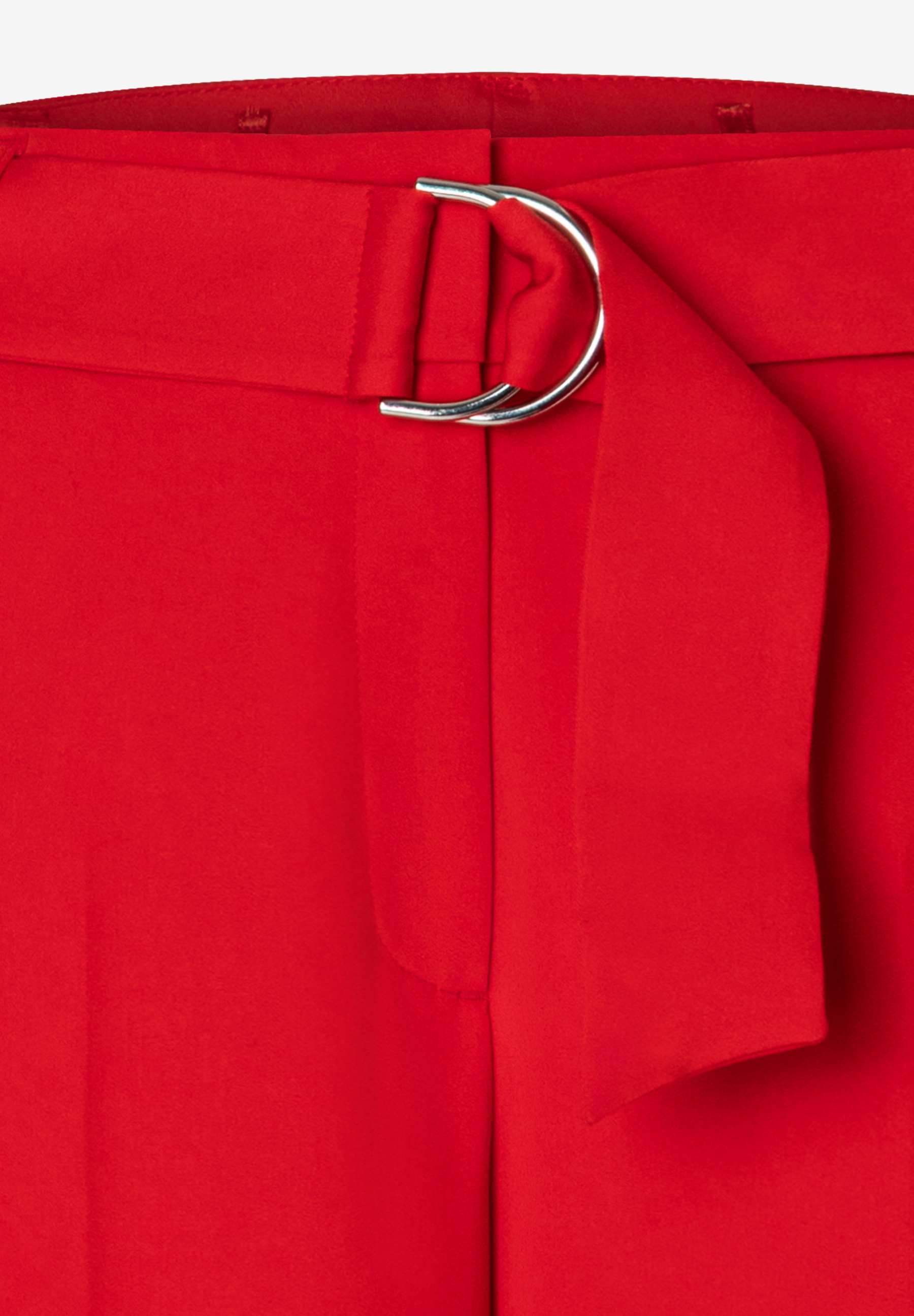 Detailaufnahme der roten MORE & MORE Hose mit fließendem Stoff und silberner D-Ring-Schnalle. Detailaufnahme der roten MORE & MORE Hose mit fließendem Stoff und silberner D-Ring-Schnalle.