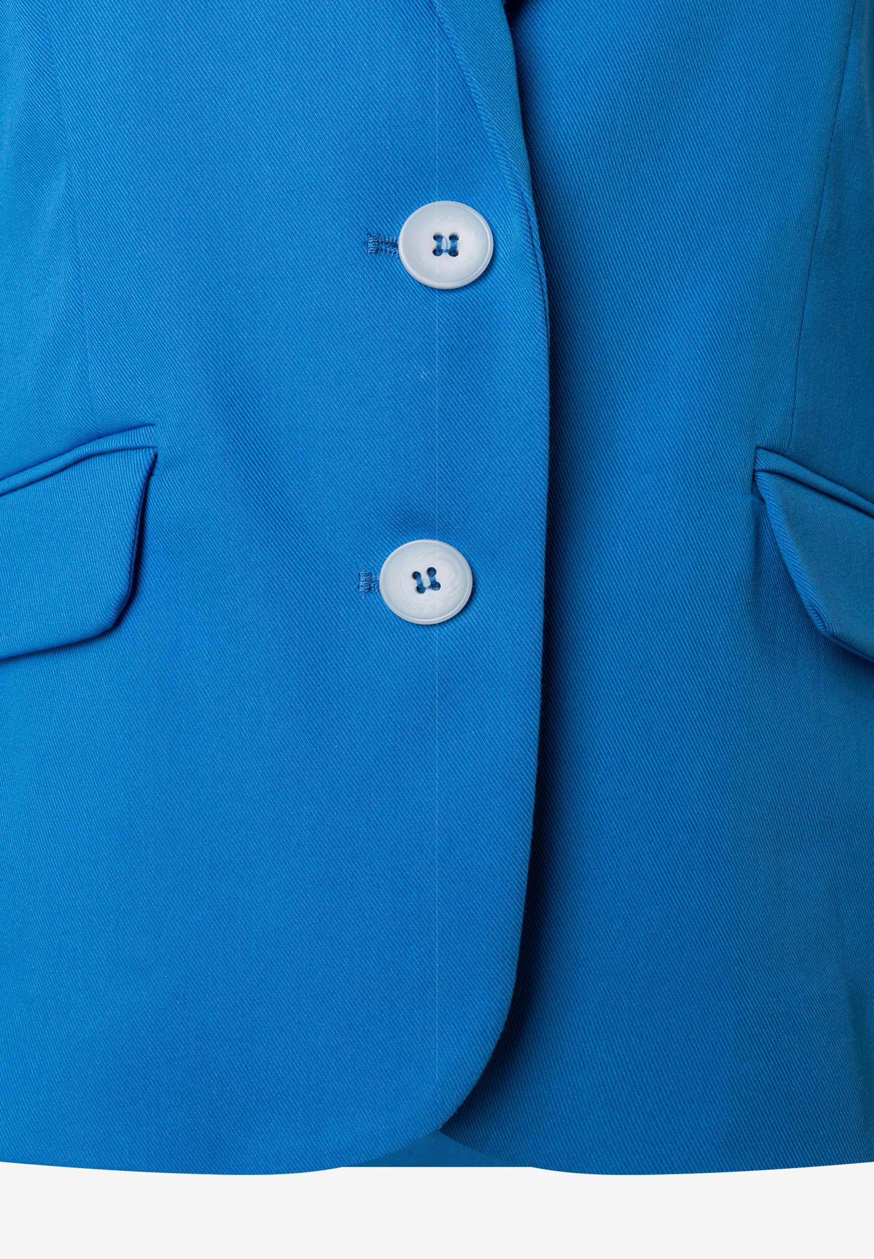 Nahaufnahme eines blauen MORE & MORE Blazers mit weißen Knöpfen und angedeuteten Taschen. Nahaufnahme eines blauen MORE & MORE Blazers mit weißen Knöpfen und angedeuteten Taschen.