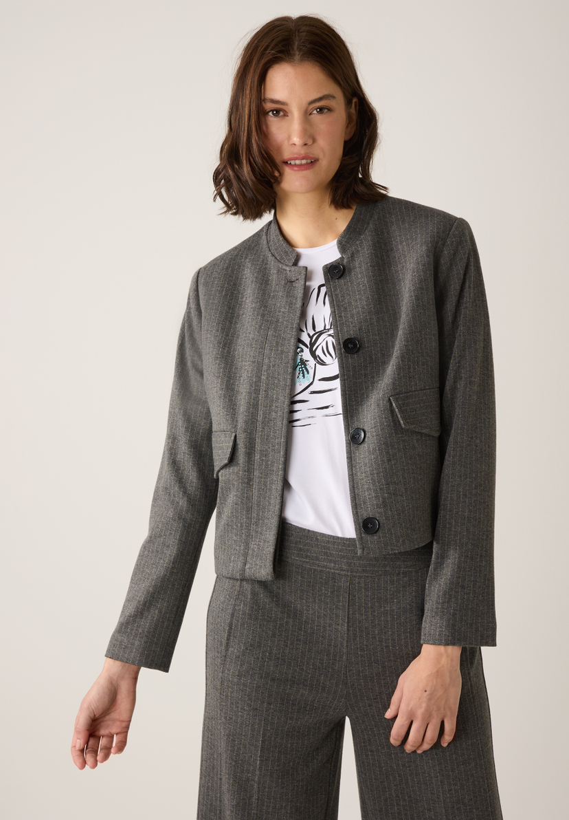 Eine Frau trägt einen grauen MORE & MORE Blazer mit Nadelstreifen über einem weißen T-Shirt. Eine Frau trägt einen grauen MORE & MORE Blazer mit Nadelstreifen über einem weißen T-Shirt.