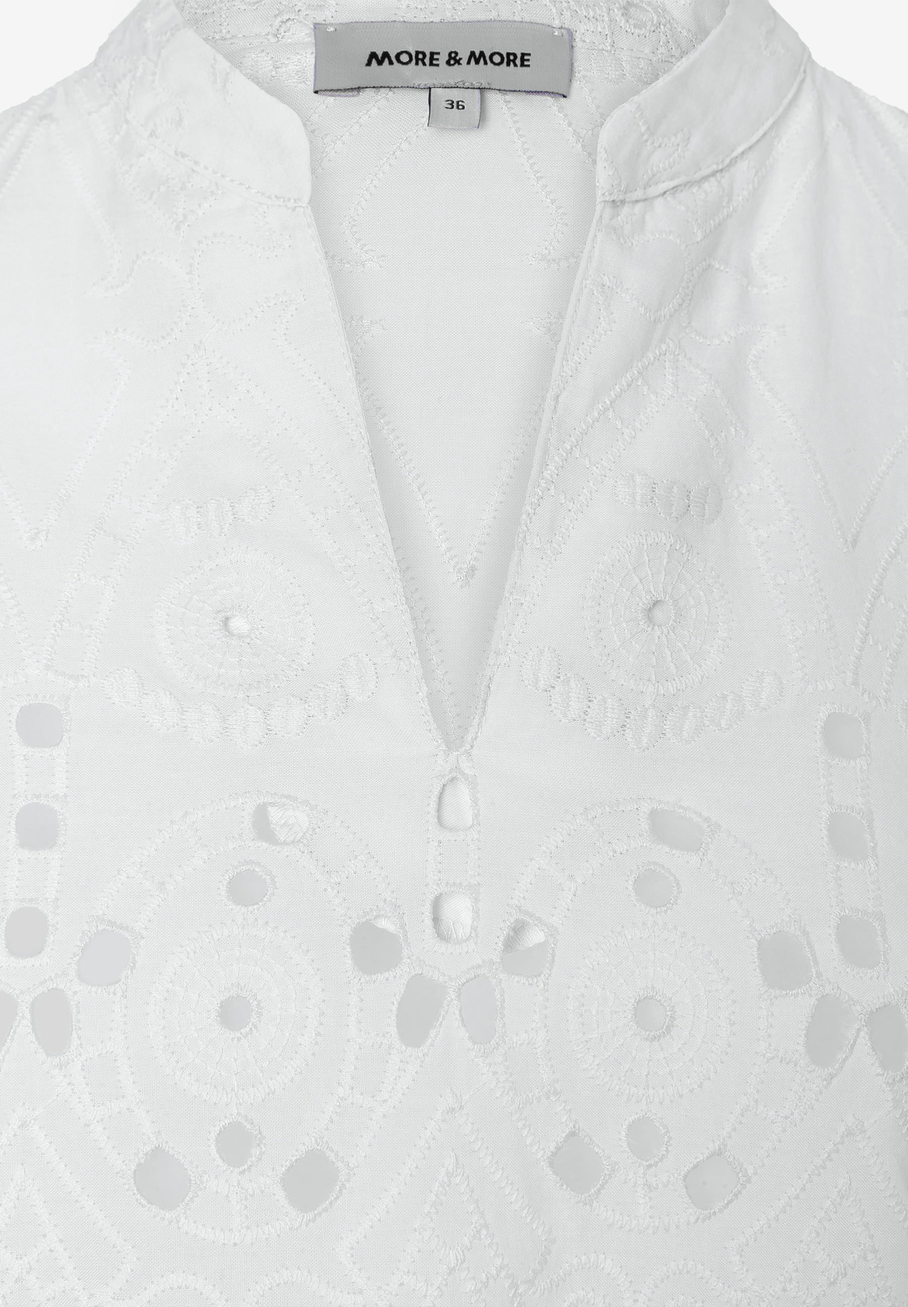 Nahaufnahme einer weißen MORE & MORE Bluse mit zarter Spitze und V-Ausschnitt. Nahaufnahme einer weißen MORE & MORE Bluse mit zarter Spitze und V-Ausschnitt.