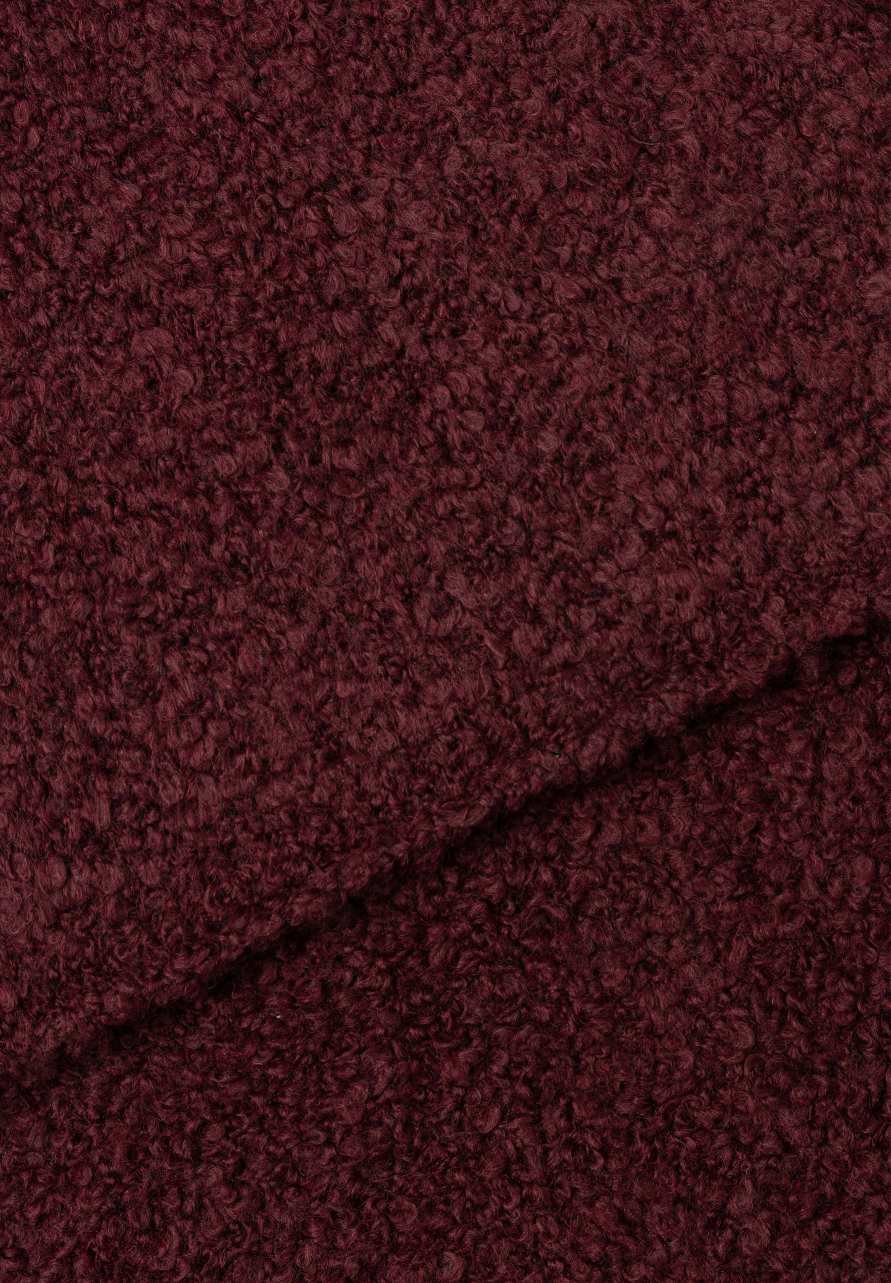 Nahaufnahme eines burgunderroten, gewellten MORE & MORE Accessoires-Stoffs mit einer Falte in der Mitte. Nahaufnahme eines burgunderroten, gewellten MORE & MORE Accessoires-Stoffs mit einer Falte in der Mitte.