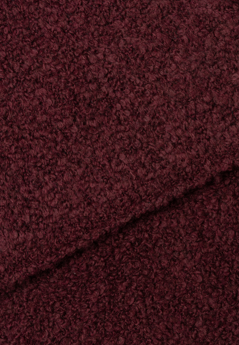 Nahaufnahme eines burgunderroten, gewellten MORE & MORE Accessoires-Stoffs mit einer Falte in der Mitte. Nahaufnahme eines burgunderroten, gewellten MORE & MORE Accessoires-Stoffs mit einer Falte in der Mitte.