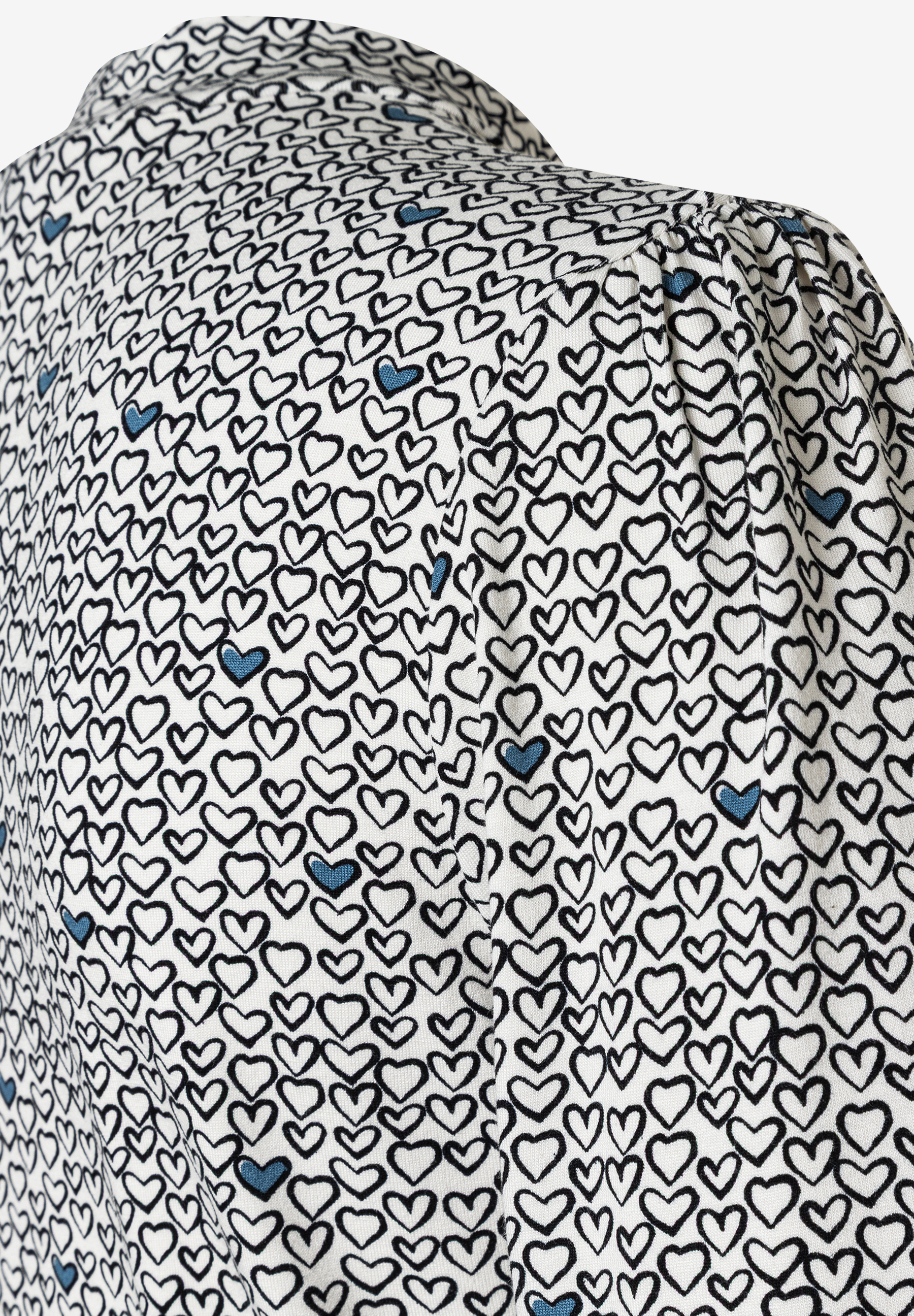 Nahaufnahme eines MORE & MORE Oberteils mit Herzmuster und Jersey-Material. Nahaufnahme eines MORE & MORE Oberteils mit Herzmuster und Jersey-Material.