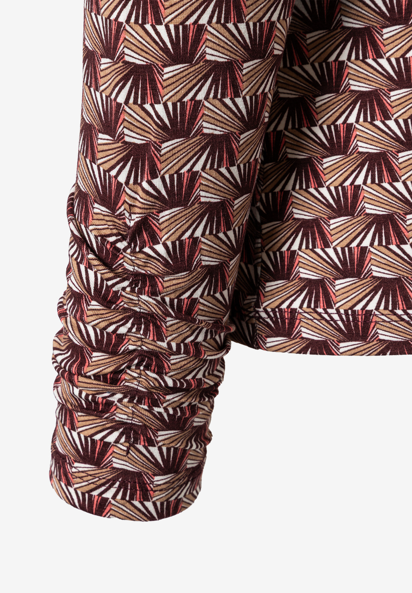 Nahaufnahme eines MORE & MORE Oberteils mit braunem, weißem und beigem Muster. Der Ärmel ist gerafft. Nahaufnahme eines MORE & MORE Oberteils mit braunem, weißem und beigem Muster. Der Ärmel ist gerafft.