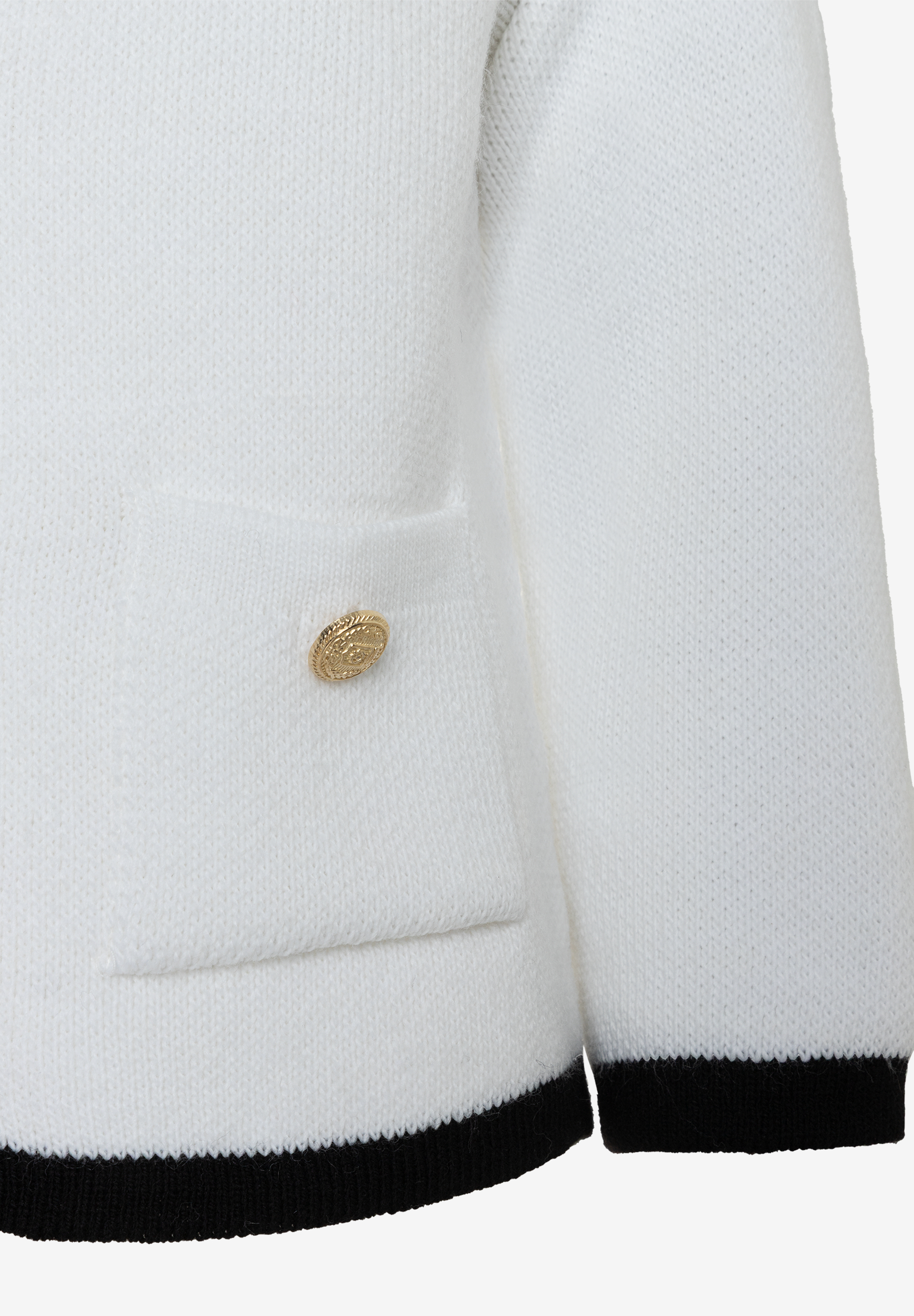 Nahaufnahme eines weißen MORE & MORE Strickpullovers mit goldfarbenem Knopf an der Tasche und schwarzem Saum. Nahaufnahme eines weißen MORE & MORE Strickpullovers mit goldfarbenem Knopf an der Tasche und schwarzem Saum.