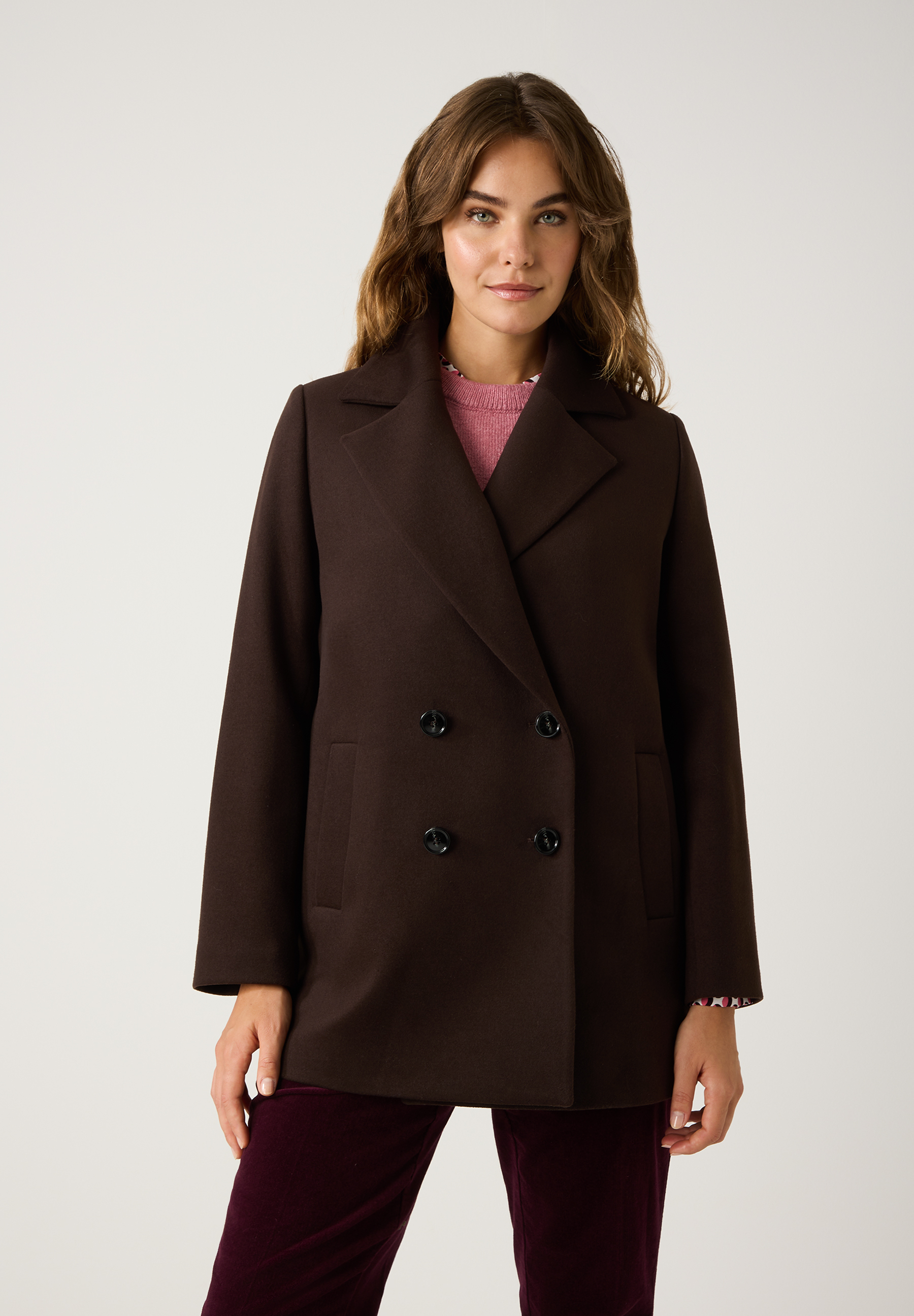 Eine Frau trägt einen braunen MORE & MORE Webware-Mantel, ein bequemes Oberteil, vor einem neutralen Hintergrund. Eine Frau trägt einen braunen MORE & MORE Webware-Mantel, ein bequemes Oberteil, vor einem neutralen Hintergrund.