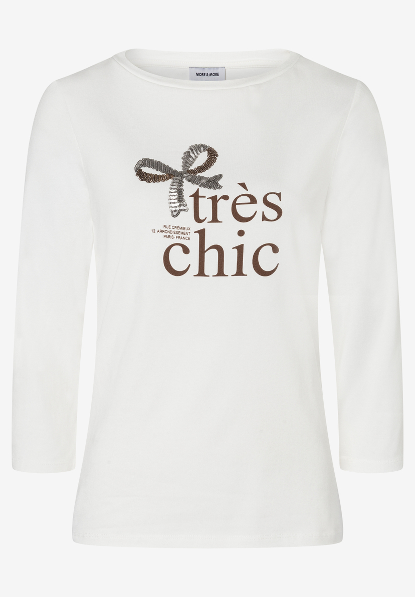 Ein weißes MORE & MORE Oberteil mit "Très Chic" Schriftzug und Schleife. Ein weißes MORE & MORE Oberteil mit "Très Chic" Schriftzug und Schleife.