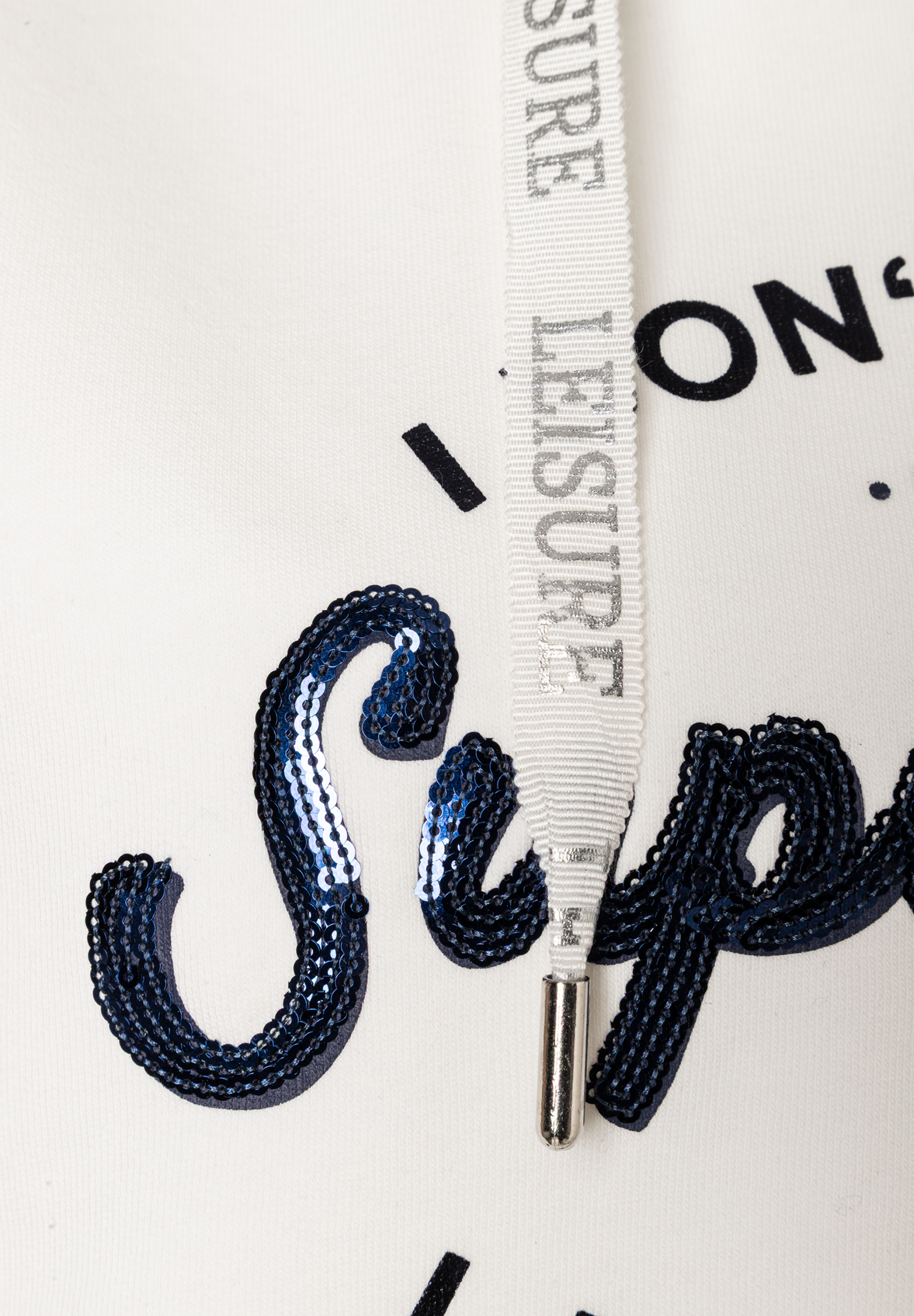Nahaufnahme eines MORE & MORE Sweatshirts mit Kordelzug und blauem Pailletten-Detail. Nahaufnahme eines MORE & MORE Sweatshirts mit Kordelzug und blauem Pailletten-Detail.