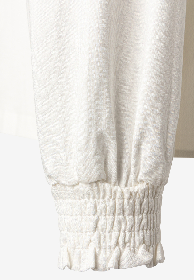 MORE & MORE Bluse: Detailaufnahme des gekräuselten, gerüschten Ärmelbunds einer cremeweißen Bluse.